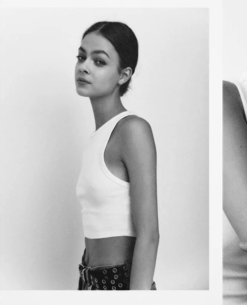 Woman wearing white top and jeans near the white background