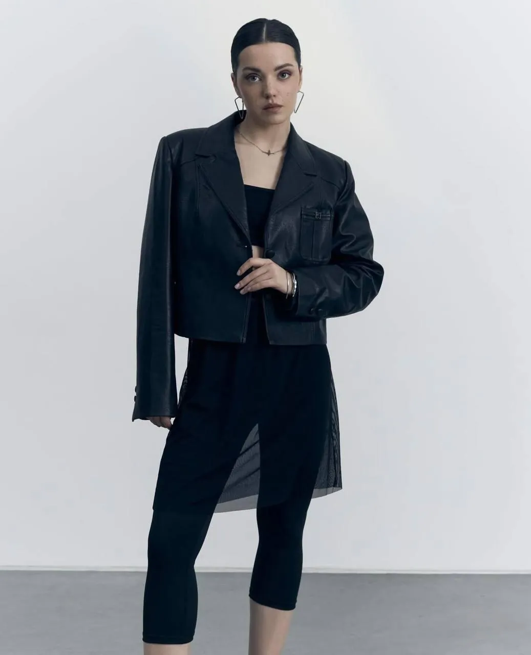 Woman with a black blazer standing calmly in the studio