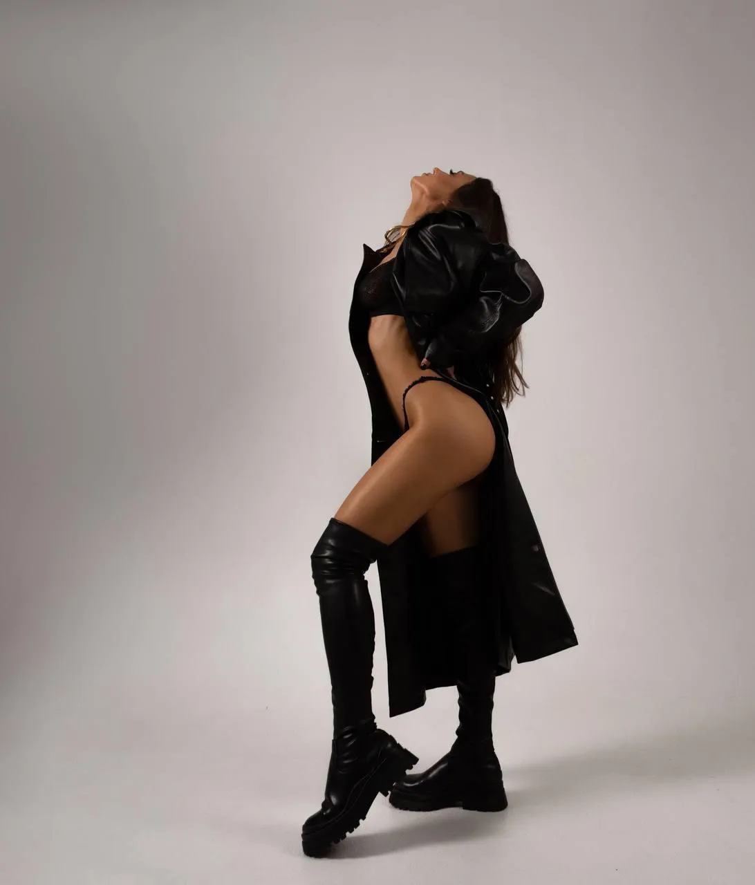 Woman with a black outfit with boots standing in the studio