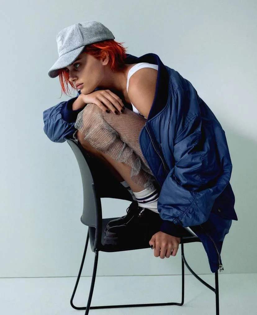 Woman with cap sitting on a chair with tattooed leg visible