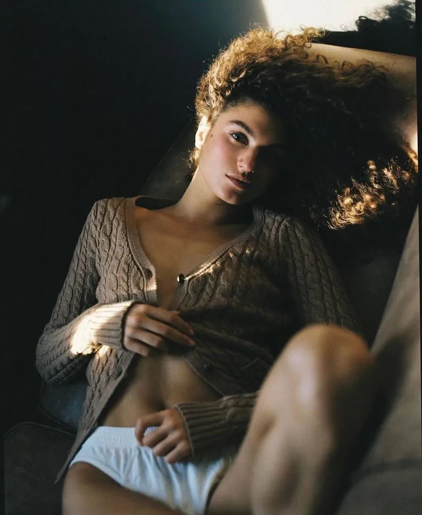 Woman with curly hair sitting and looking at the camera