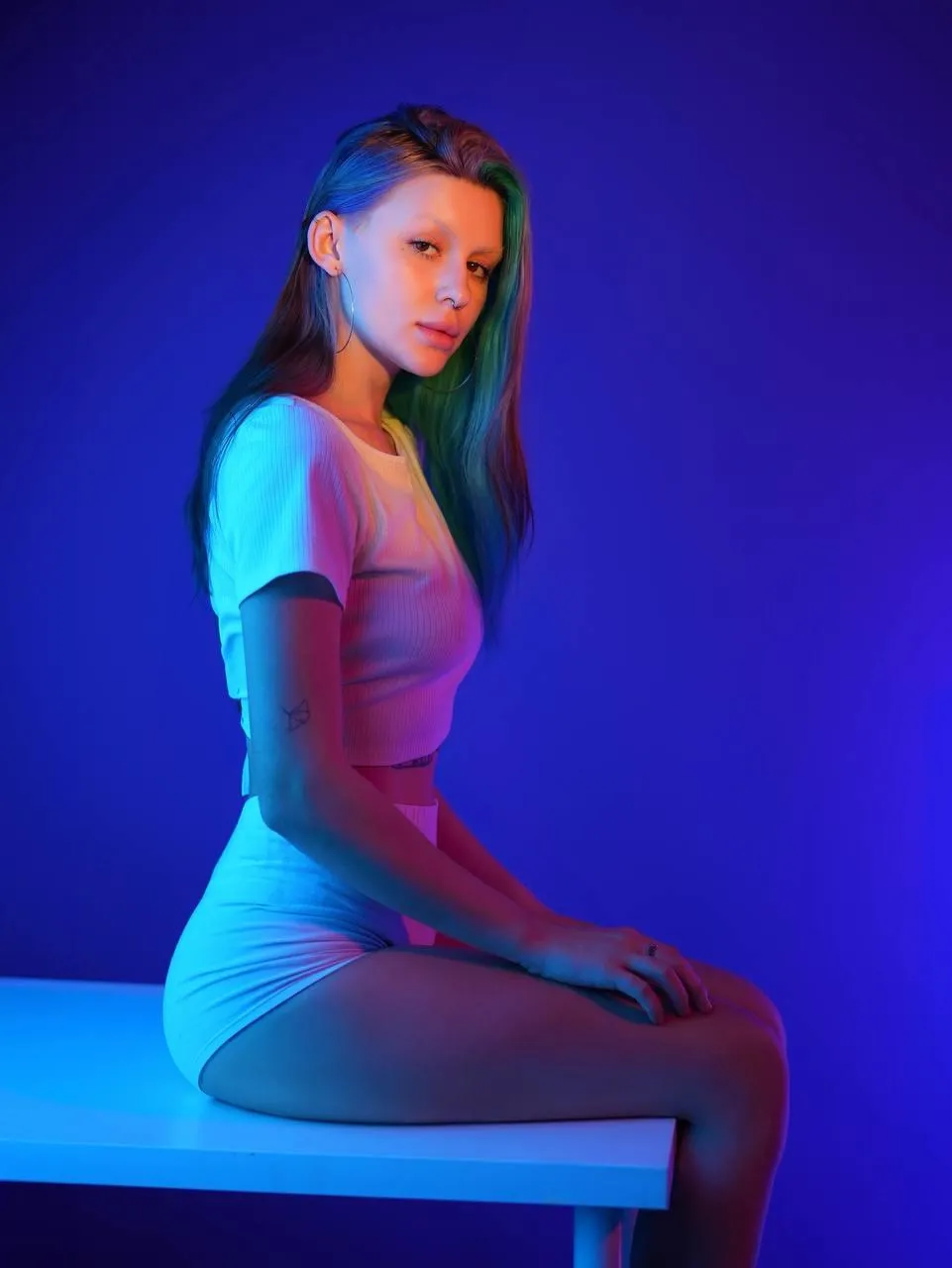 Woman with makeup and face highlight sitting on a table