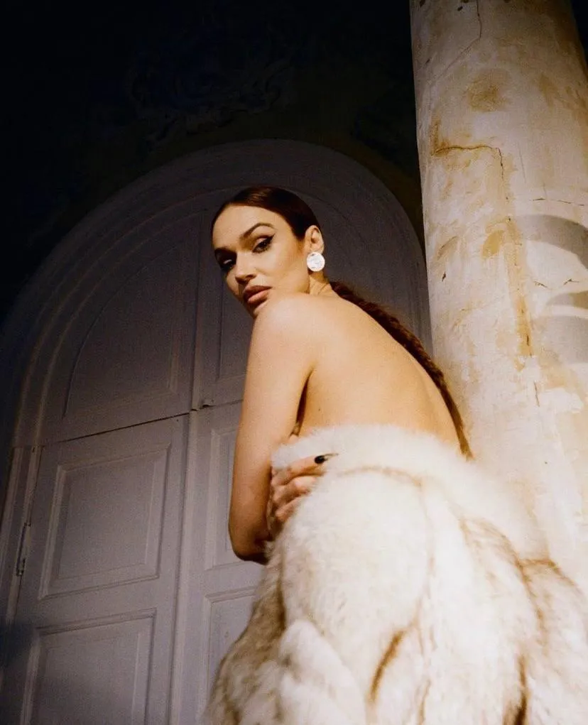 Woman wrapped in a white towel standing by a pillar indoors