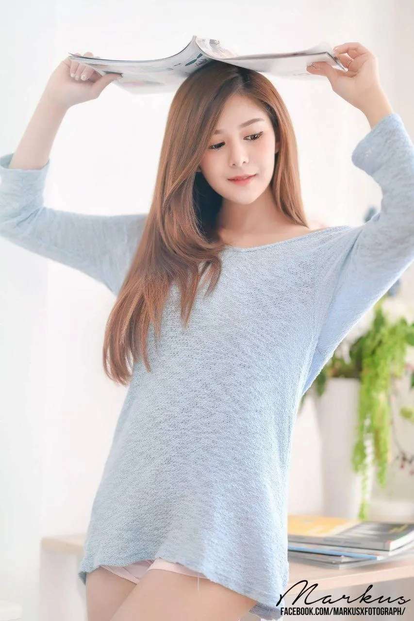 Young Woman in a Cozy Sweater And a Book on Her Head Image