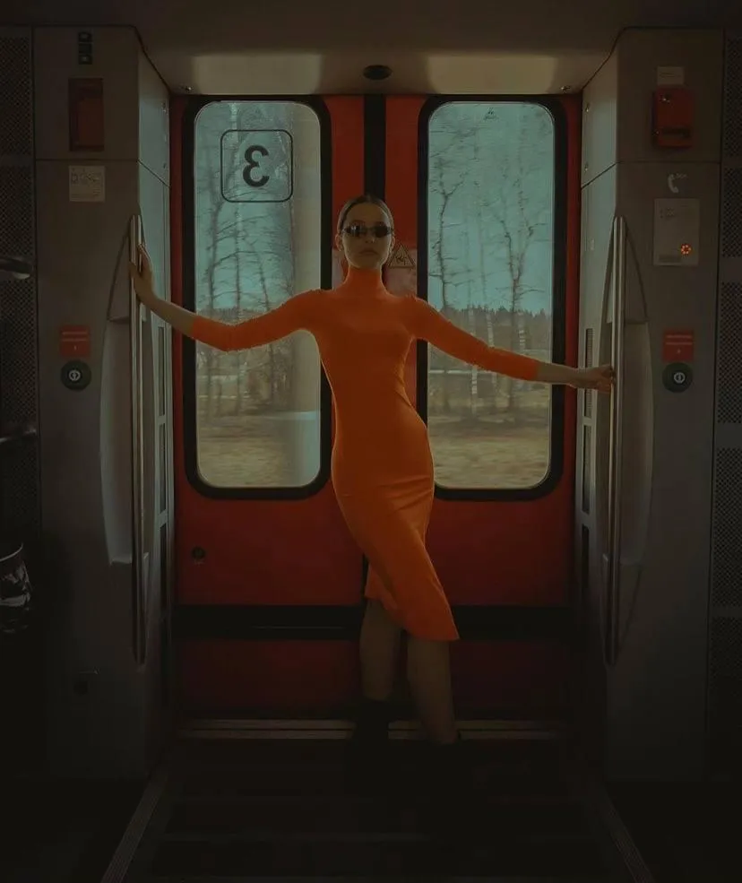 Young woman in an orange outfit standing near the train door
