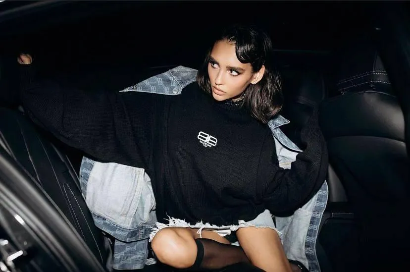 Young woman in an oversized black dress sitting in a car