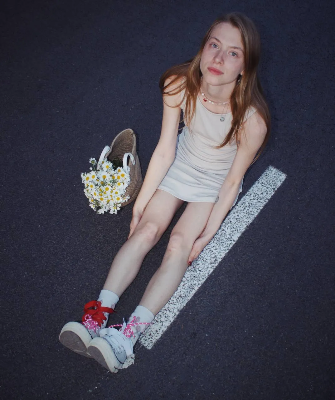 Young Woman Sitting on the Road with Flowers And Sneakers