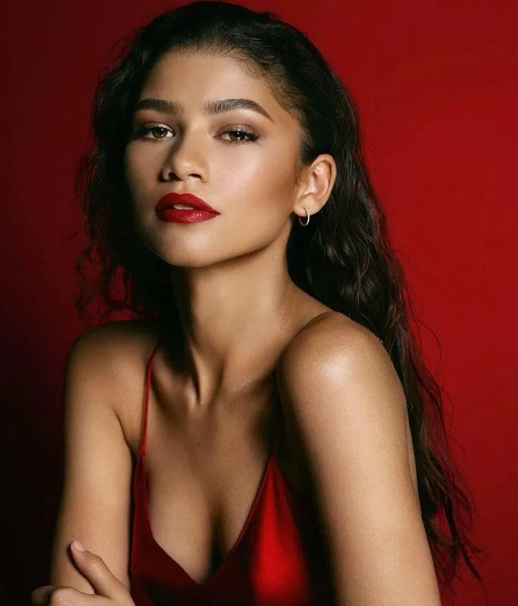 Zendaya in a red outfit standing near the red background