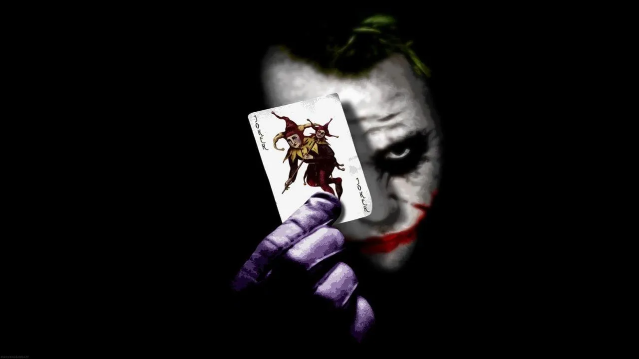 Joker Holding Playing Card in Dark High Resolution Wallpaper