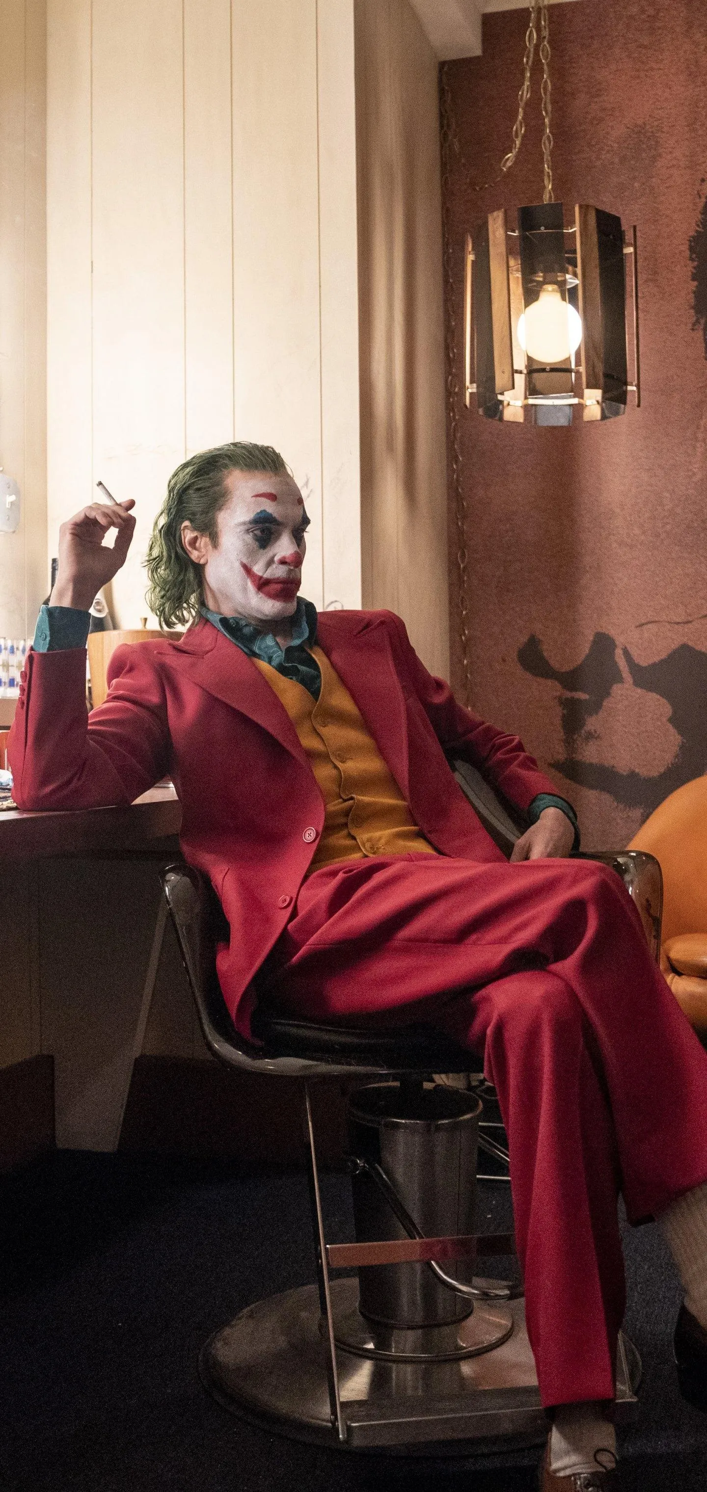 Joker in Red Suit Chair Pose Free HD Wallpaper For Mobile