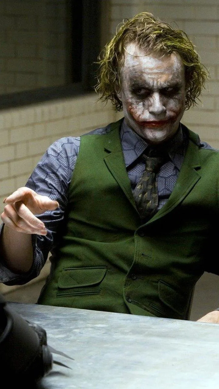 Joker Smiling in Dimly Lit Interrogation Room HD Wallpaper
