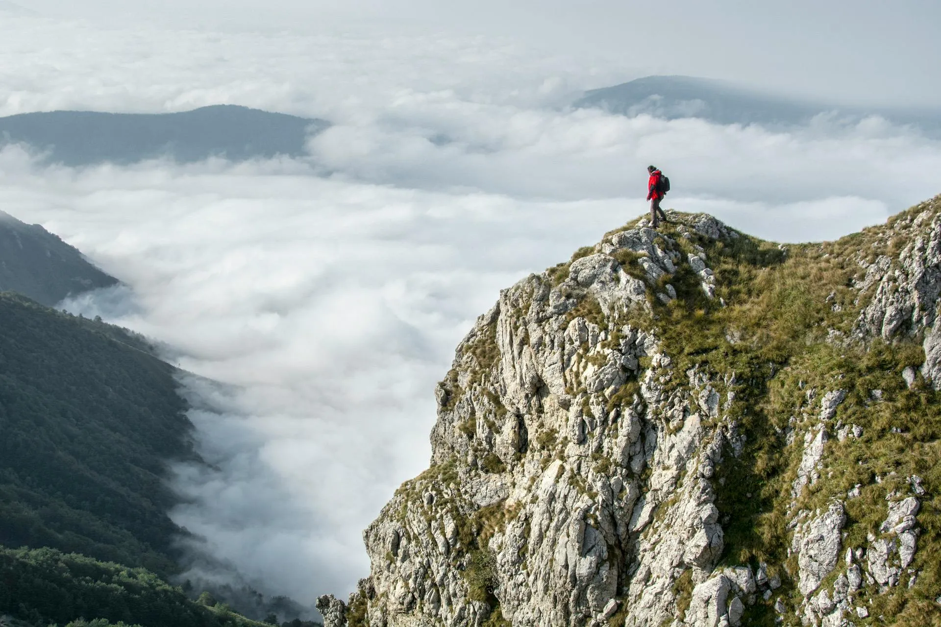 Adventurer Looks Out Over Mountain Cliff Surrounded By Fog