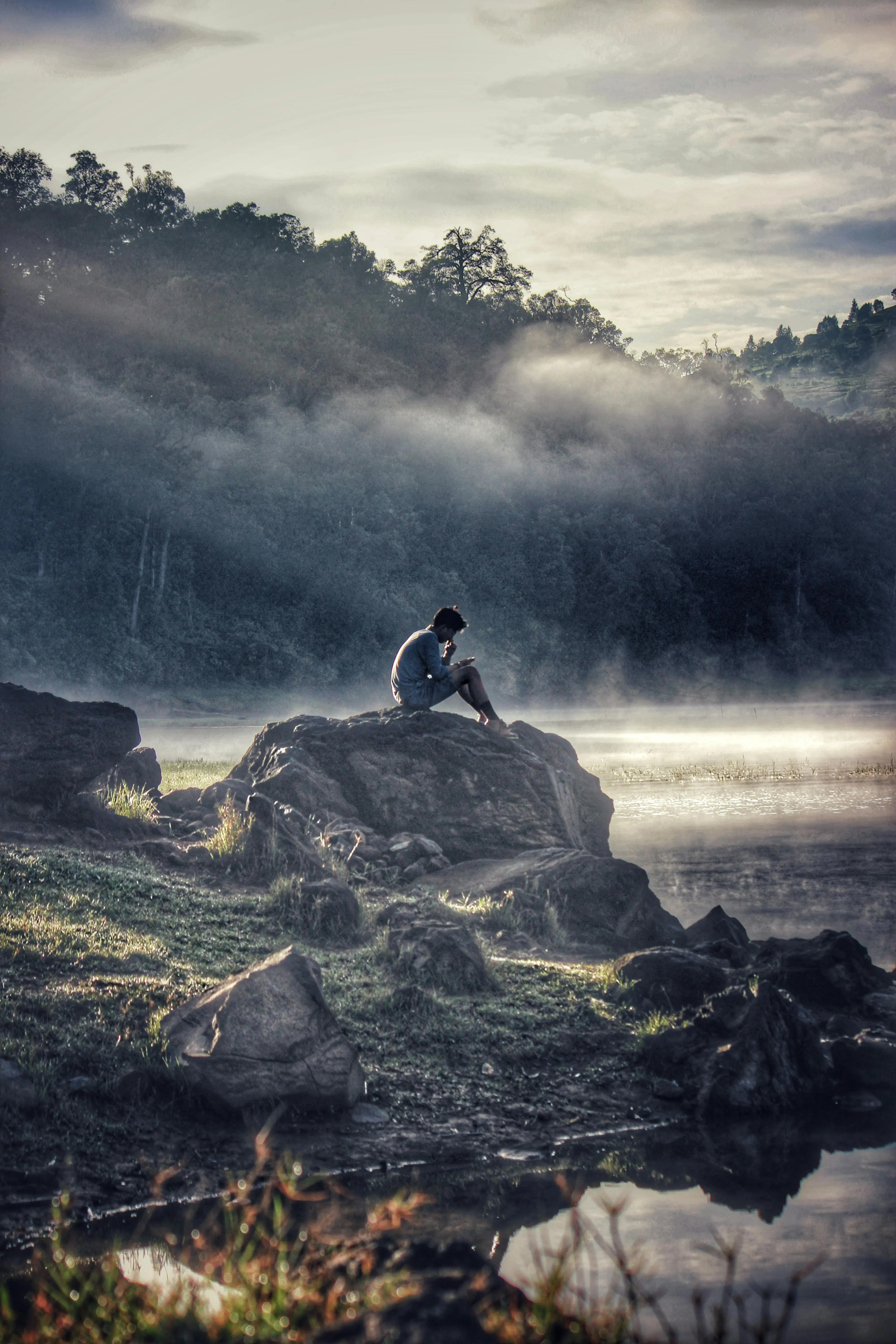 Adventurer Sitting in Misty Mountains Under Cloudy Sky