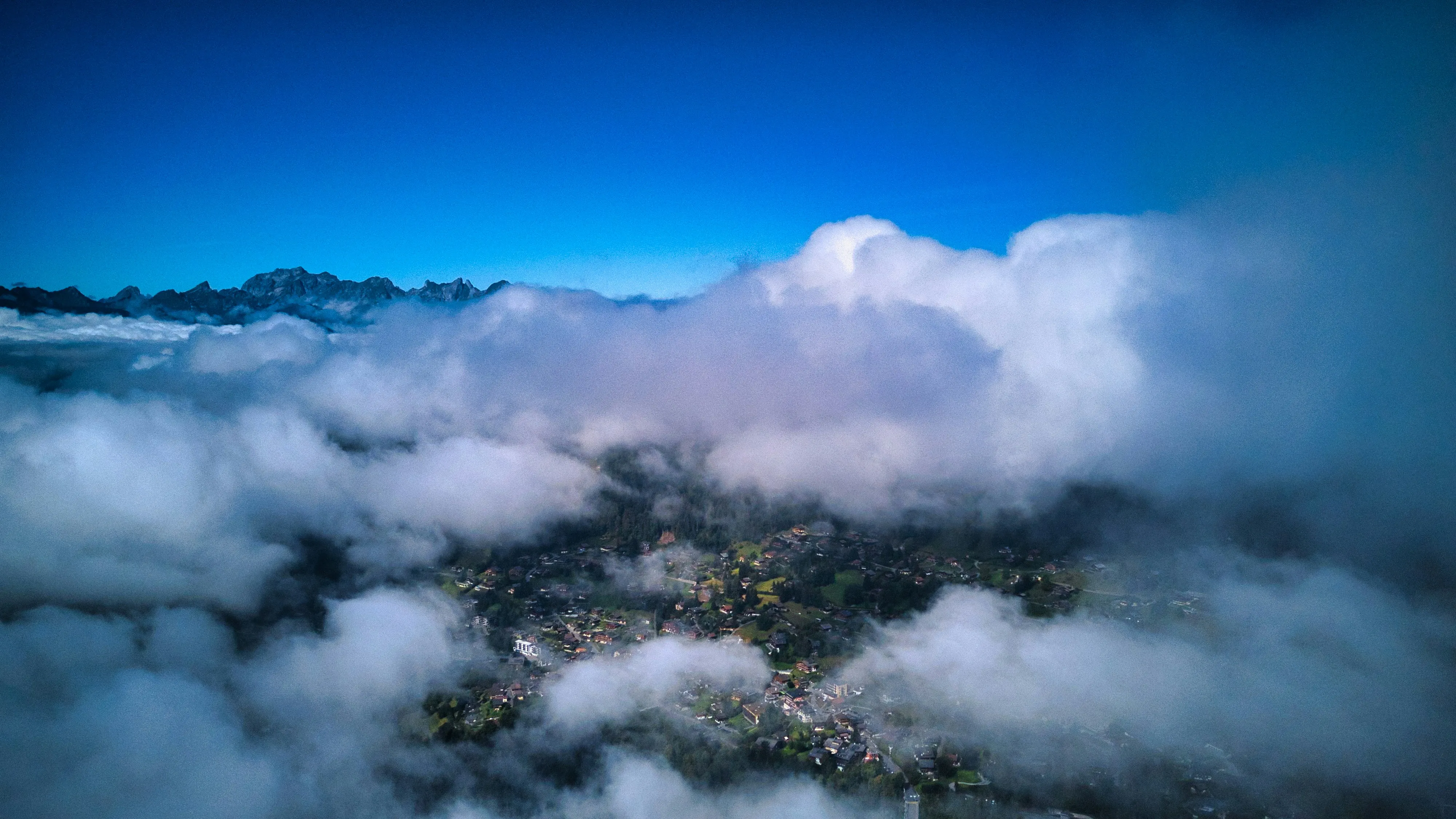 Aerial View of Clouds Over a Forested Mountain Range