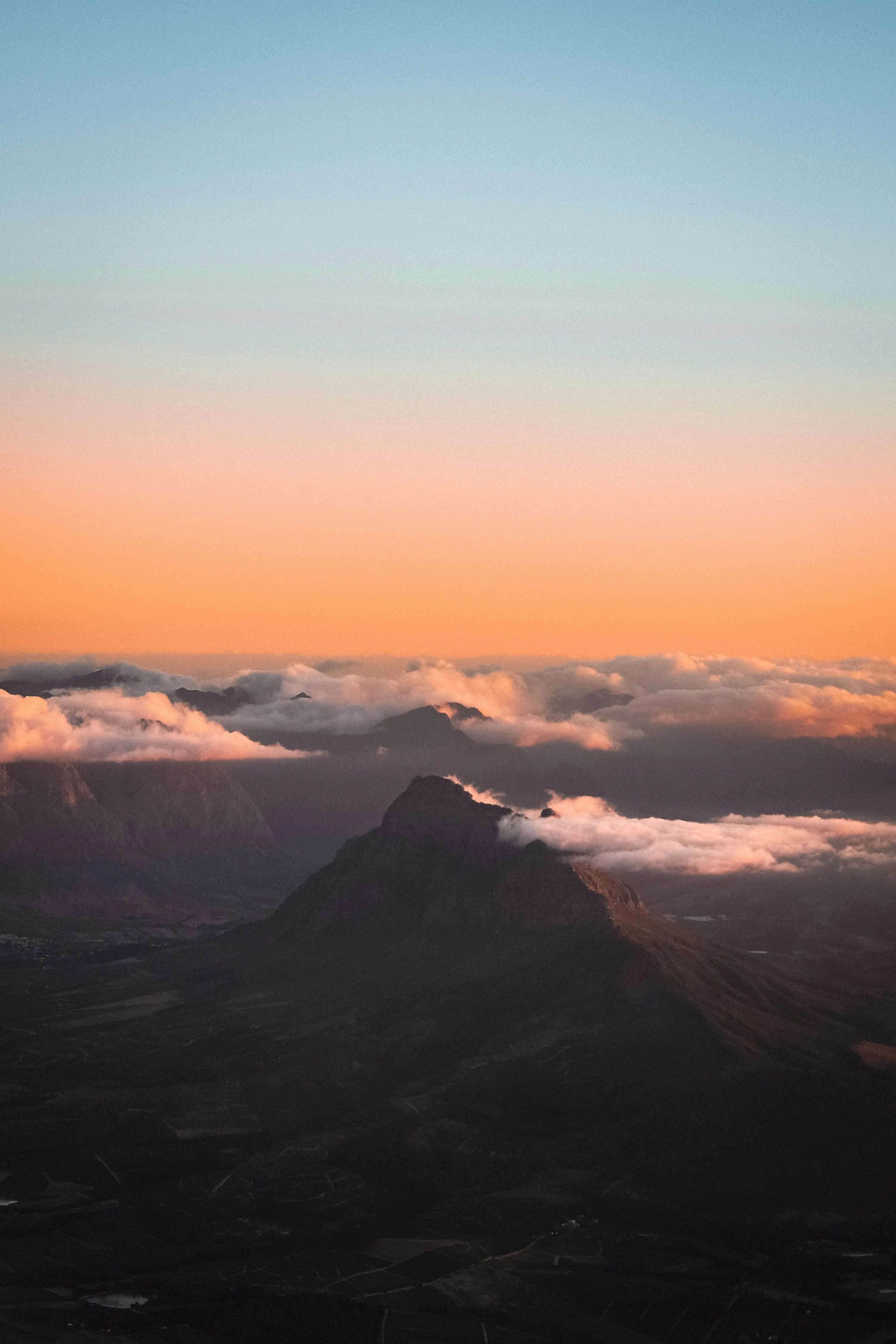 Aerial View of Mountains Peeking Through Orange Cloudscape