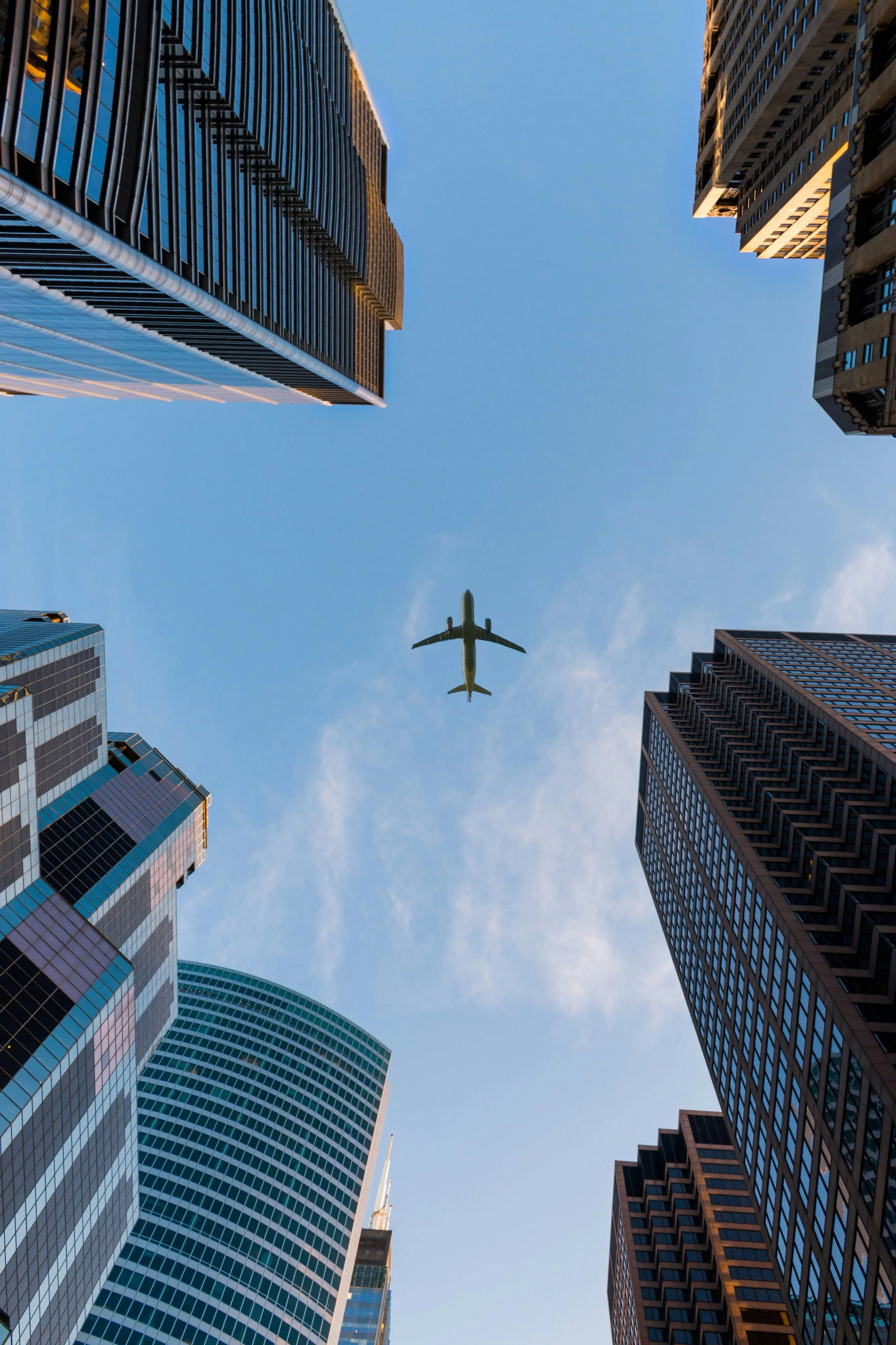 Airplane Flying Above Skyscrapers on a Clear Blue Sky Day