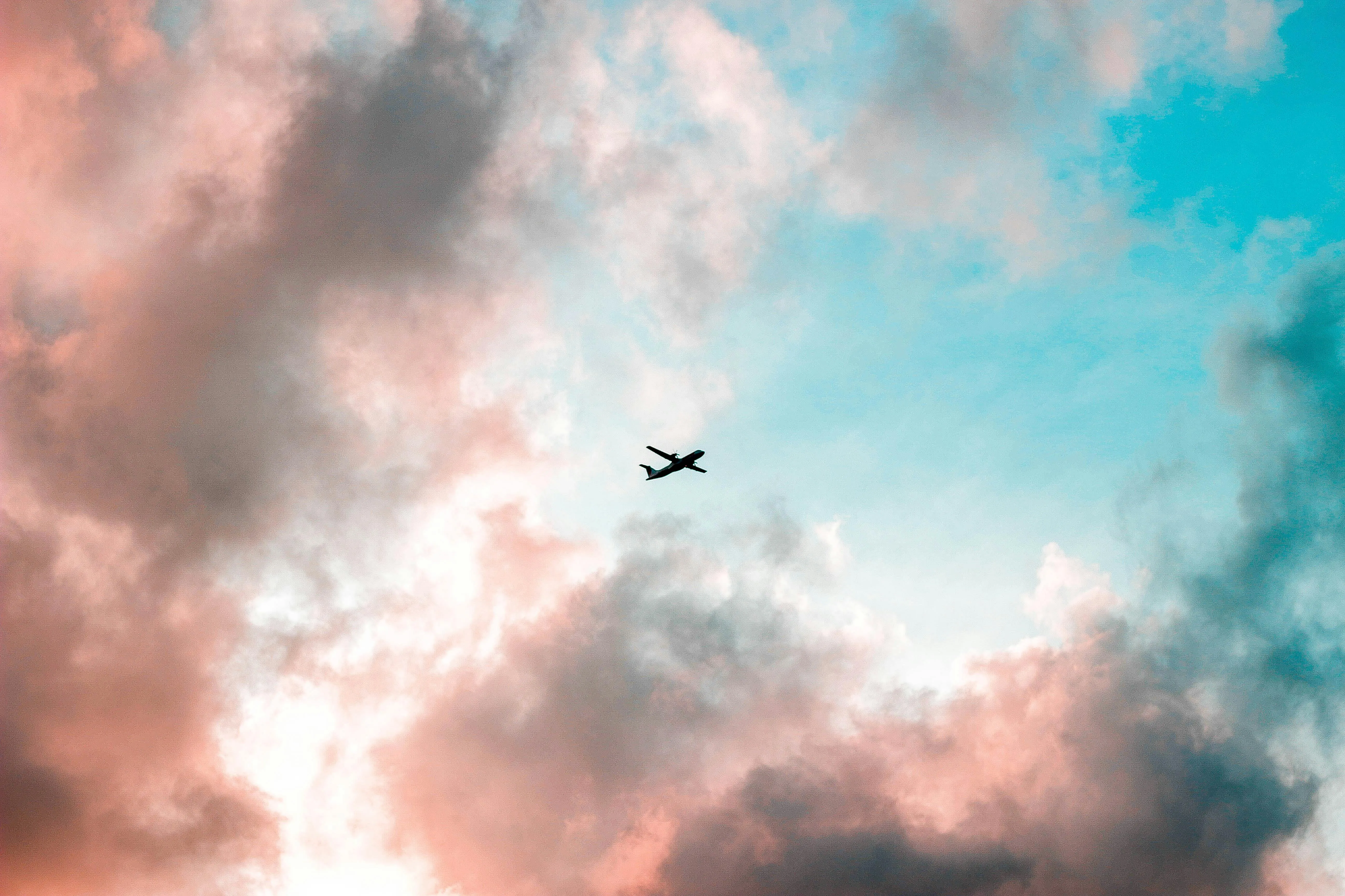 Airplane Flying High in a Colorful Cloudy Sky Wallpaper
