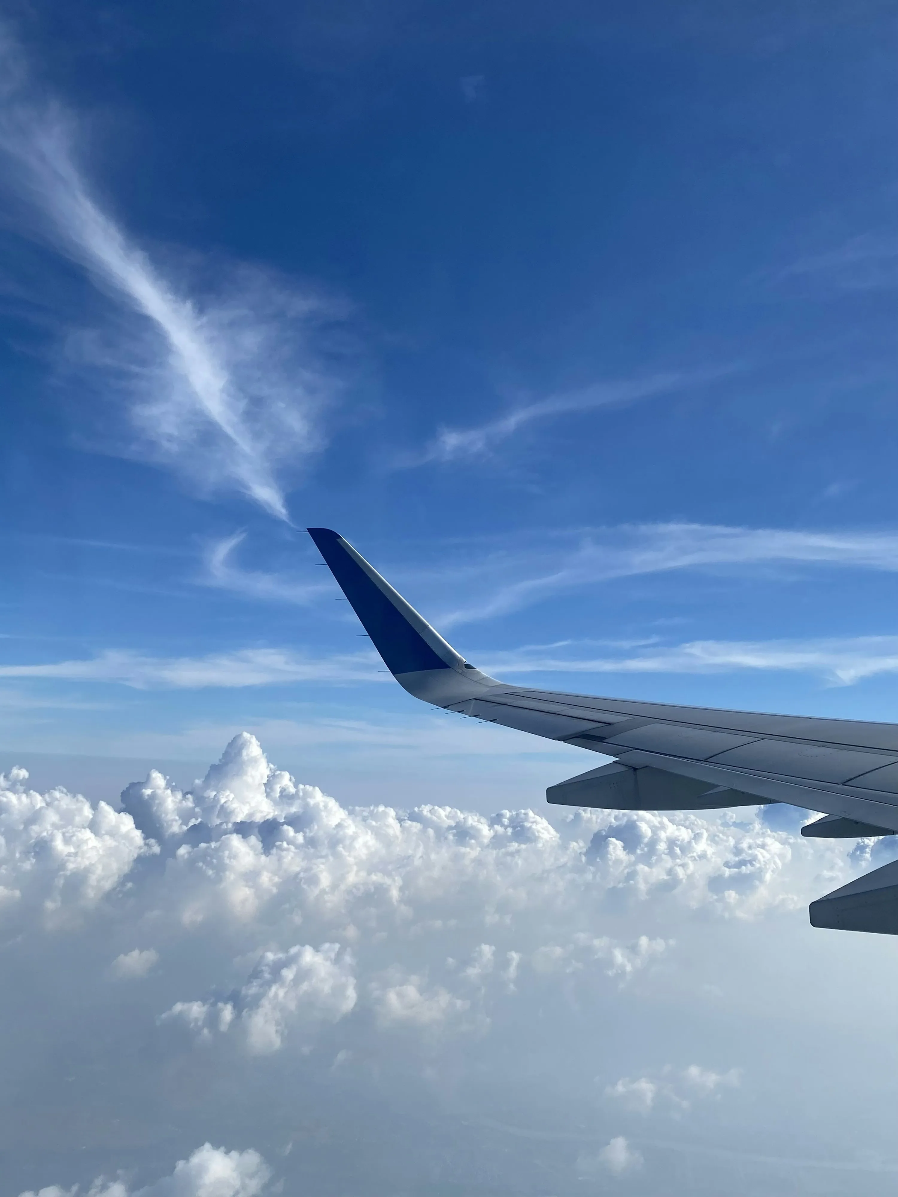 Airplane Wing Flying Above White Clouds and Blue Sky