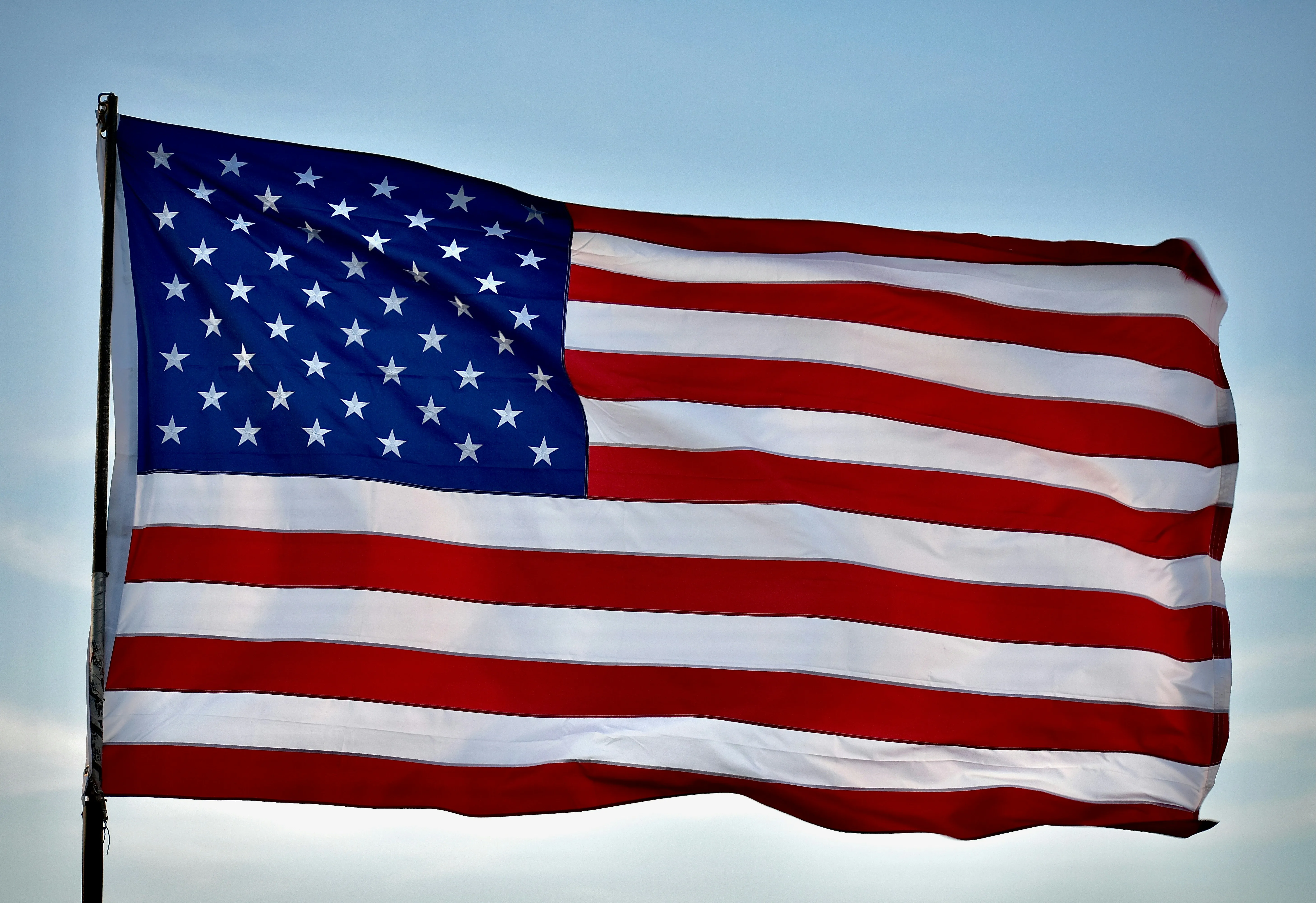 American Flag Waving in Wind Under Blue Sky with Clouds