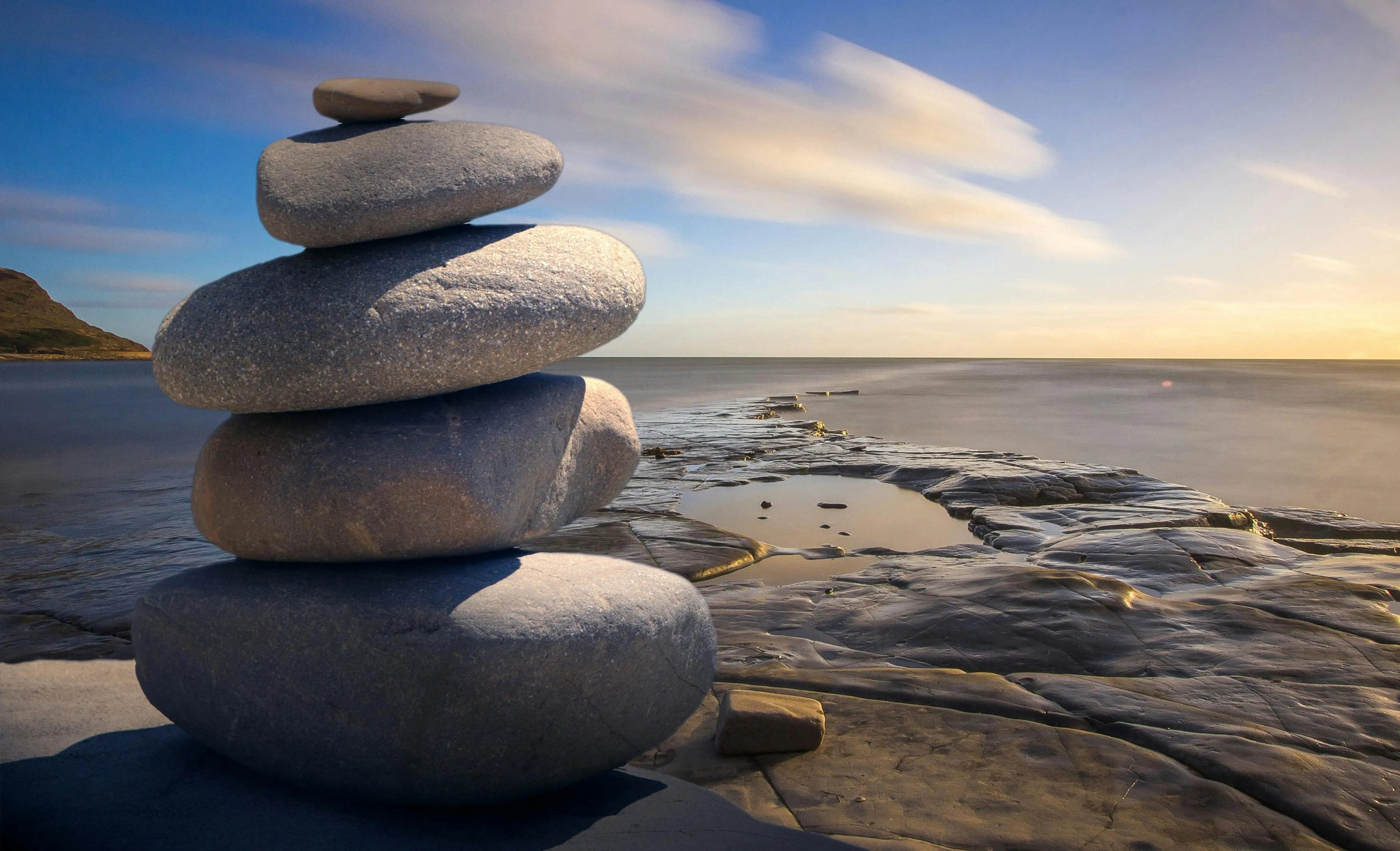 Balanced Rock Stack on Beach Under a Peaceful Sky at Sunset
