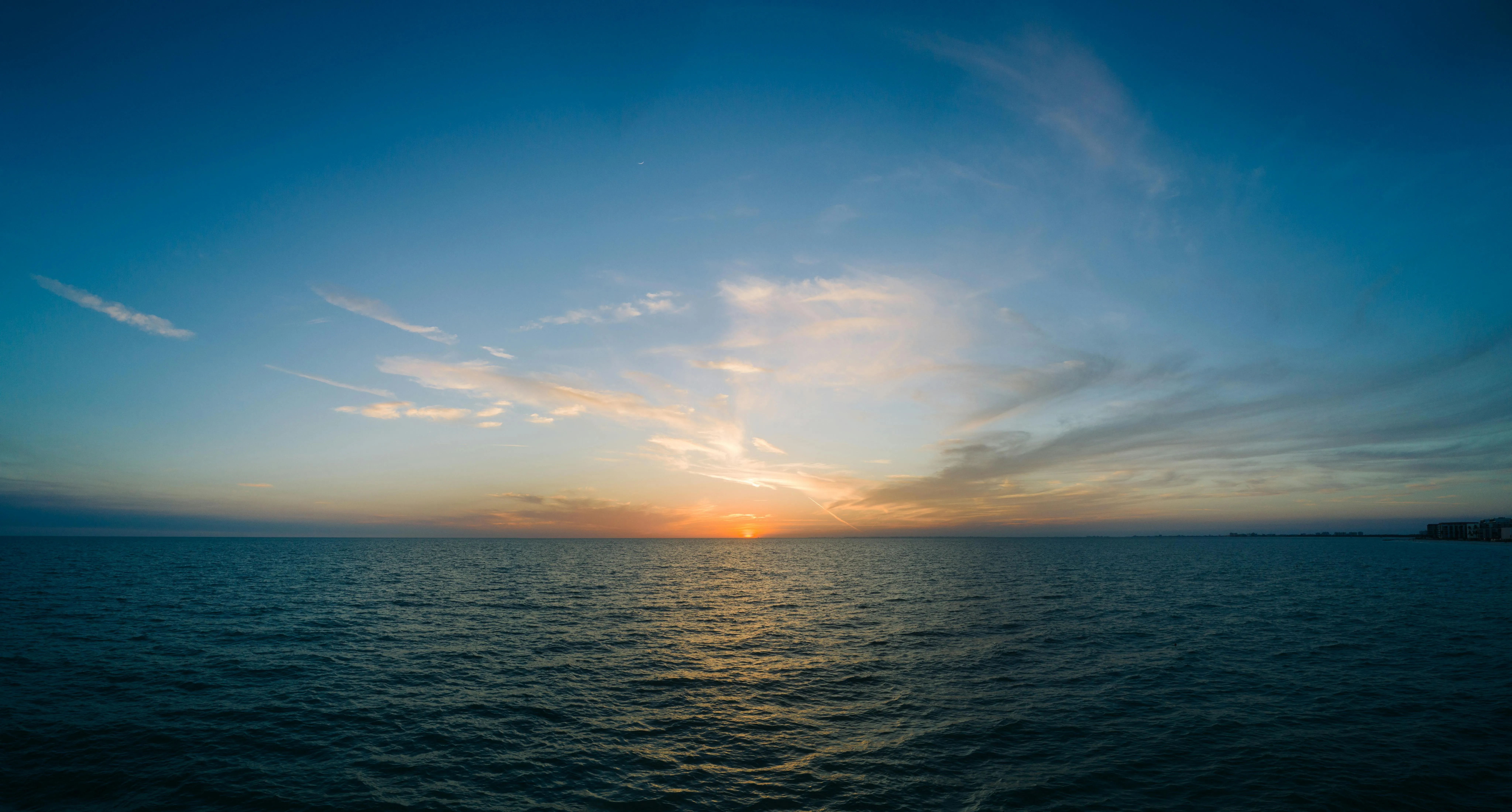 Beautiful Sunset Over Calm Ocean with Soft Clouds Image