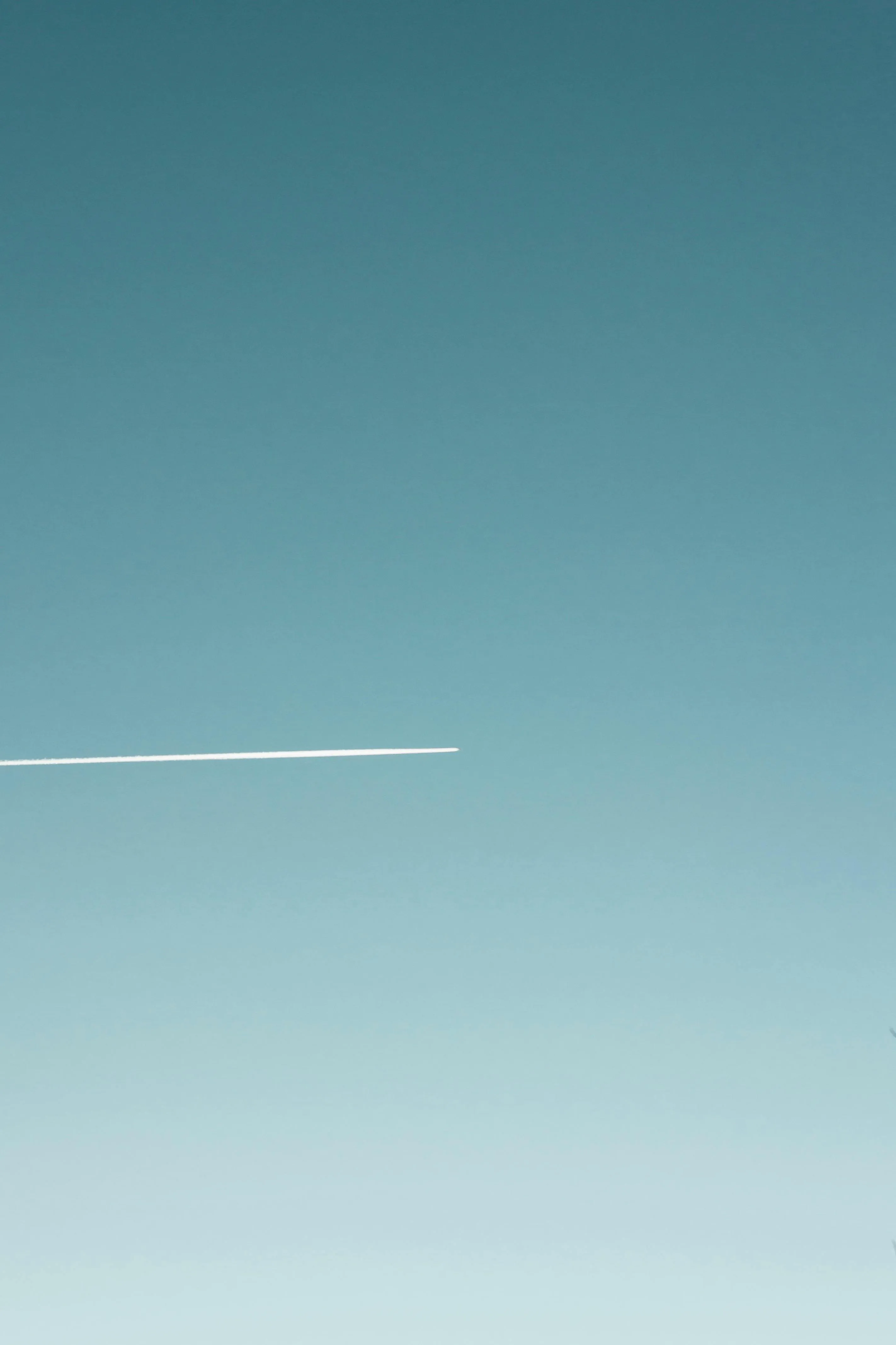 Blue Sky with Airplane Contrail Passing Through Thin Clouds