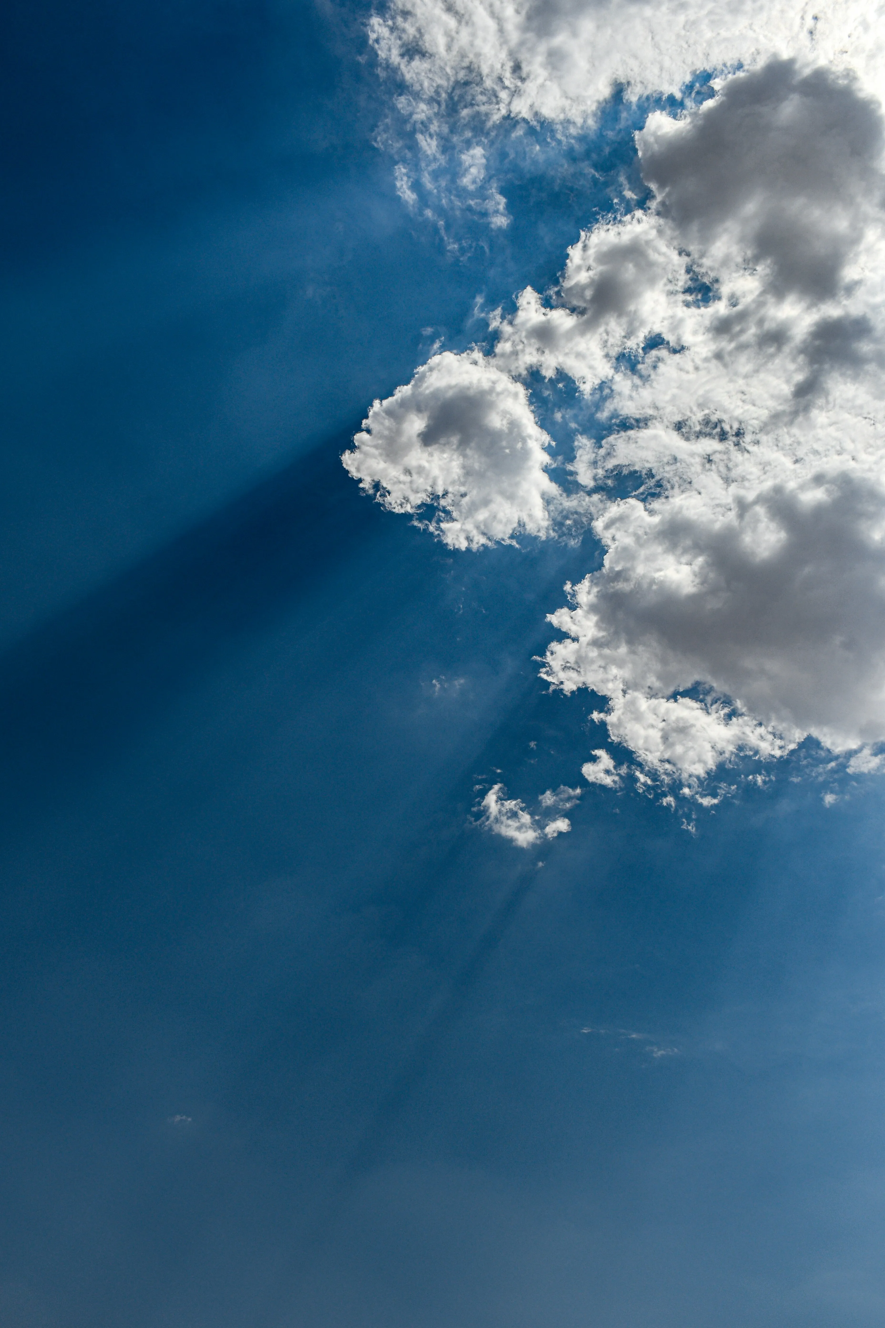 Blue Sky with Sun Rays Shining Through White Clouds