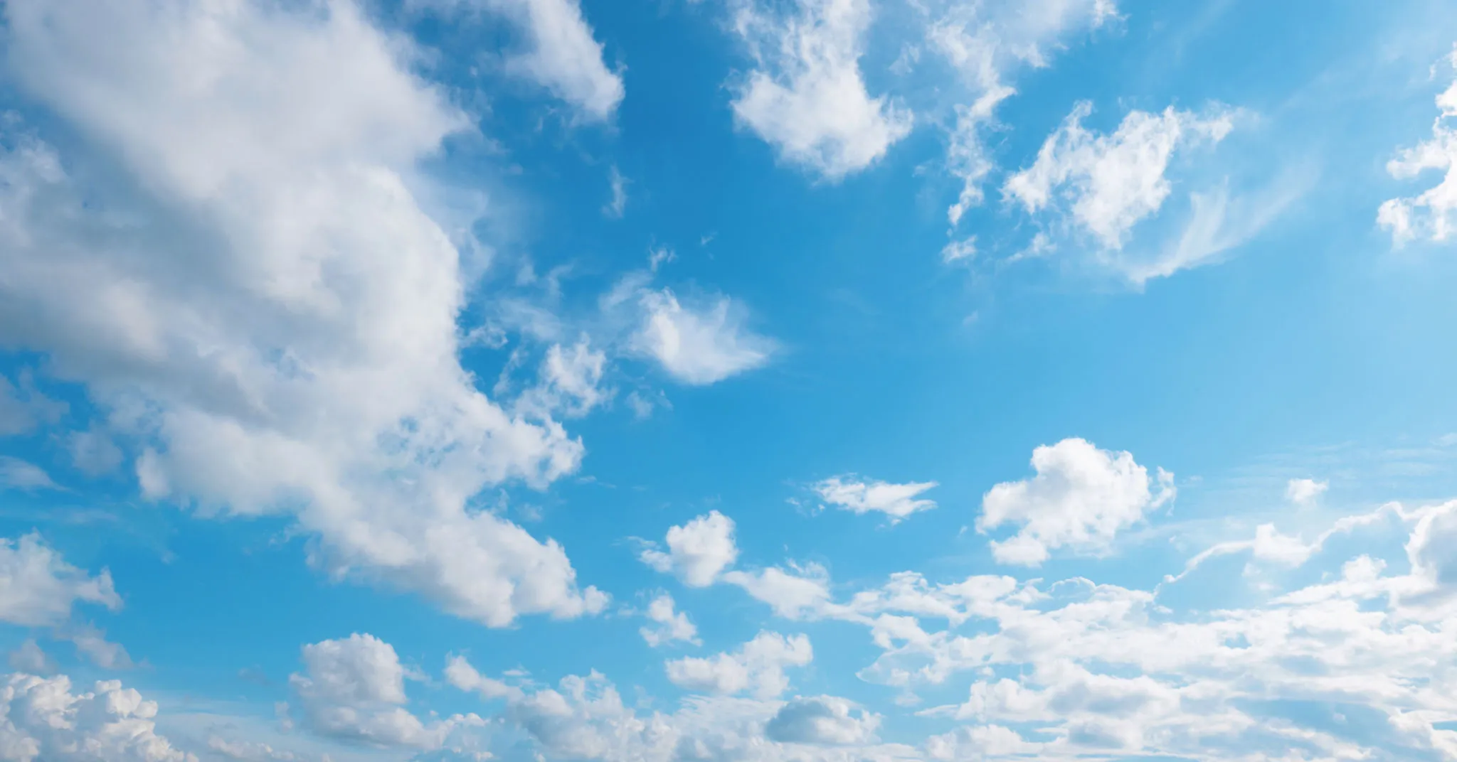 Blue Sky with White Fluffy Clouds Over Green Landscape