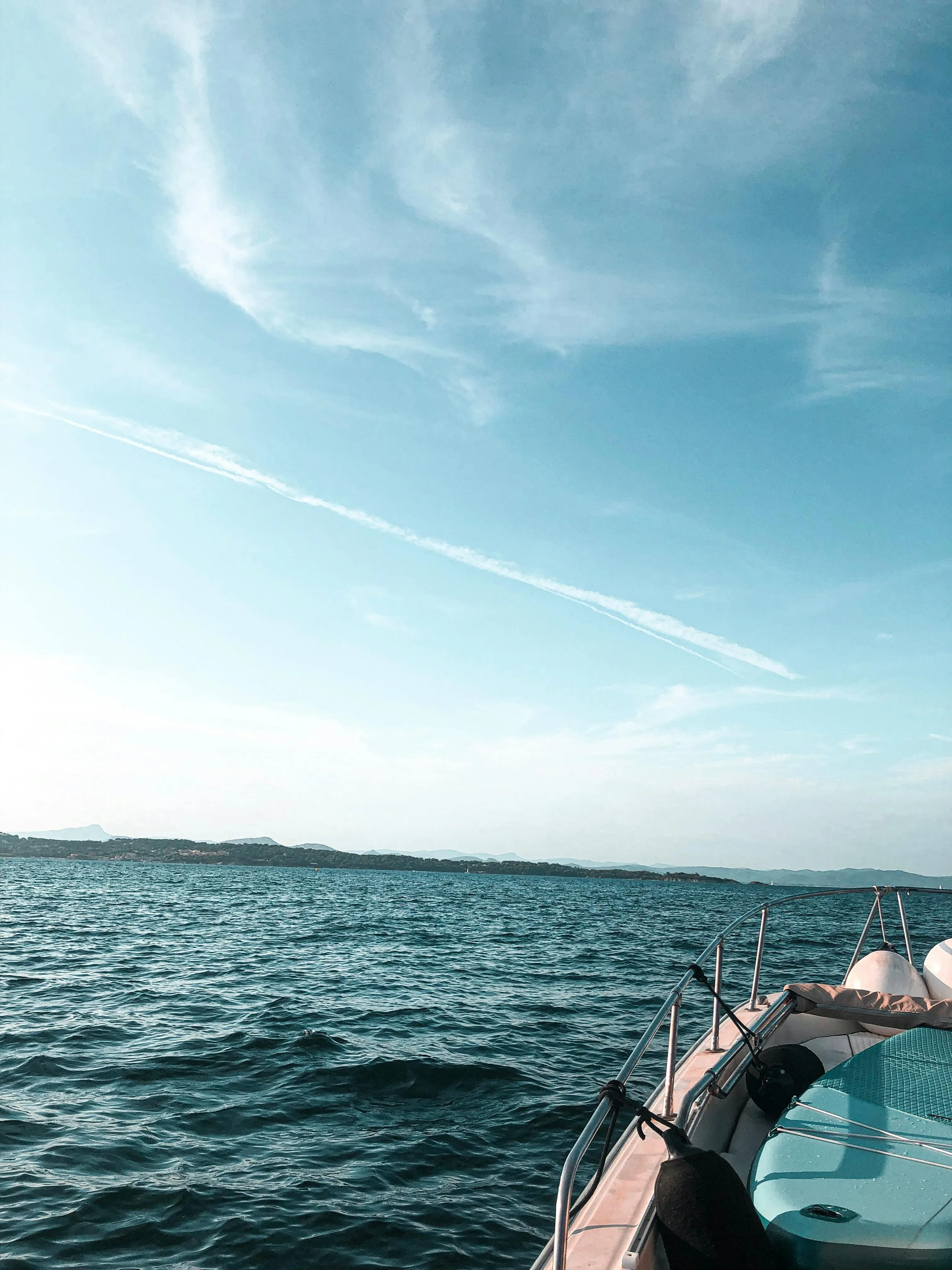 Boat Floating on Blue Water with Light Clouds Above