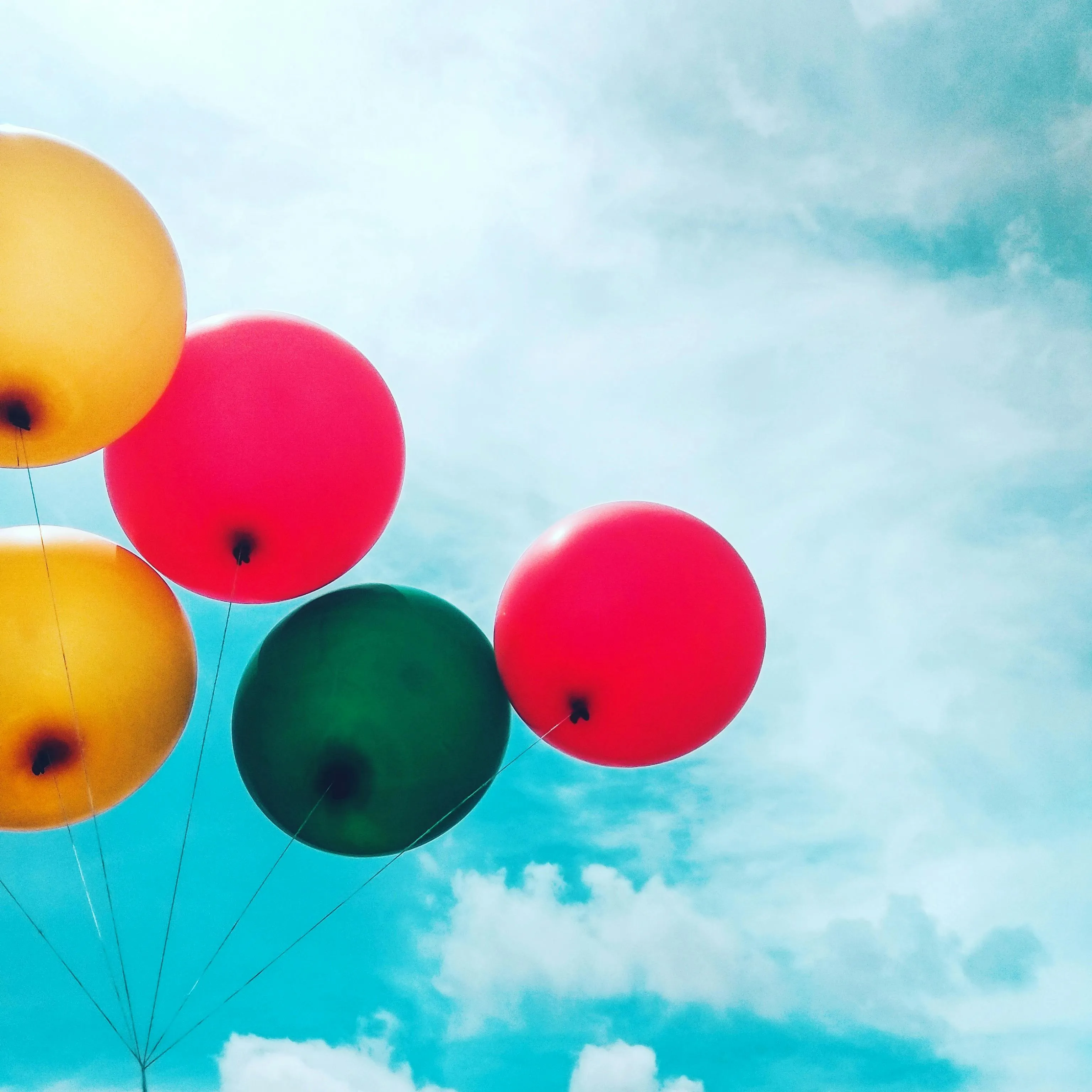 Bright Balloons Against Clear Blue Sky with Clouds