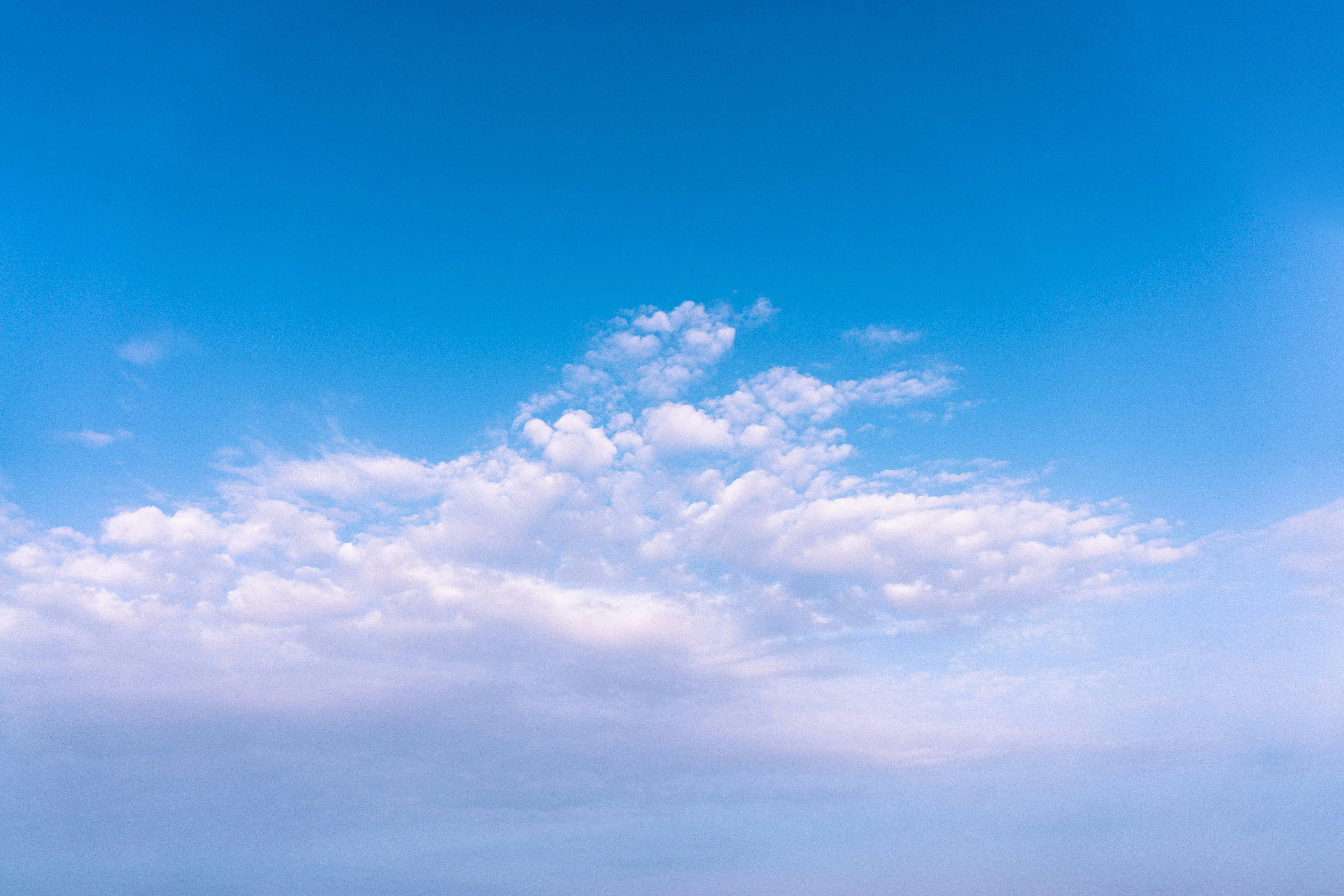 Bright Blue Sky with Clouds Above Distant Horizon Image
