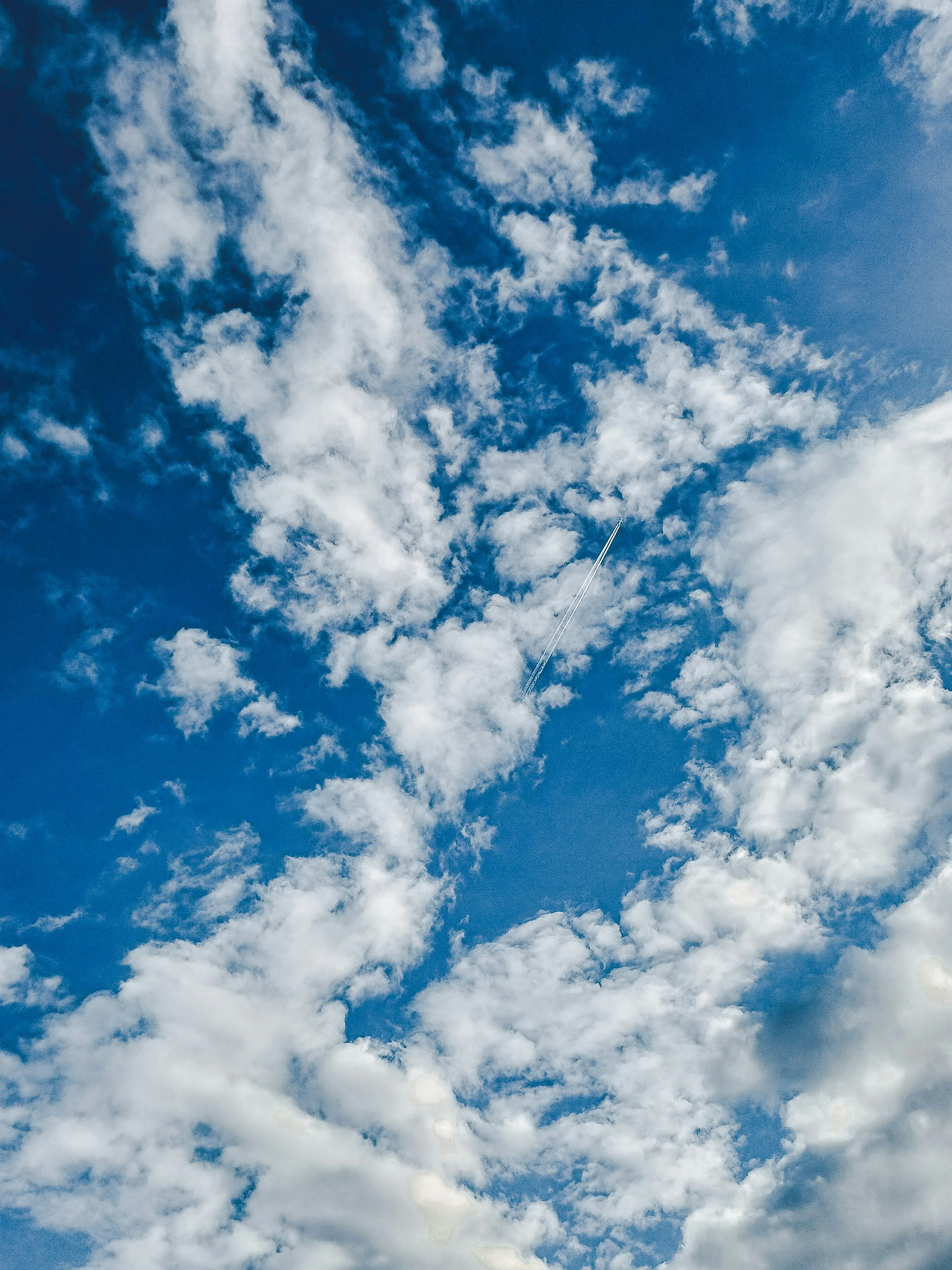 Bright Blue Sky with Scattered White Fluffy Clouds Over Mountains