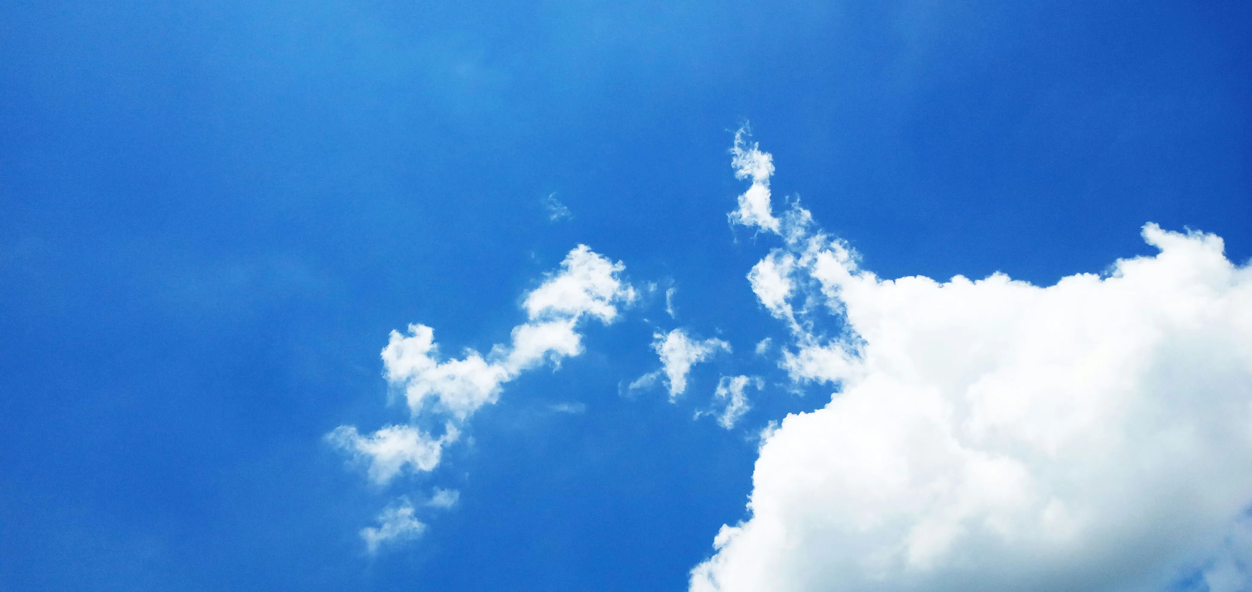 Bright Blue Sky with White Clouds Floating High Wallpaper