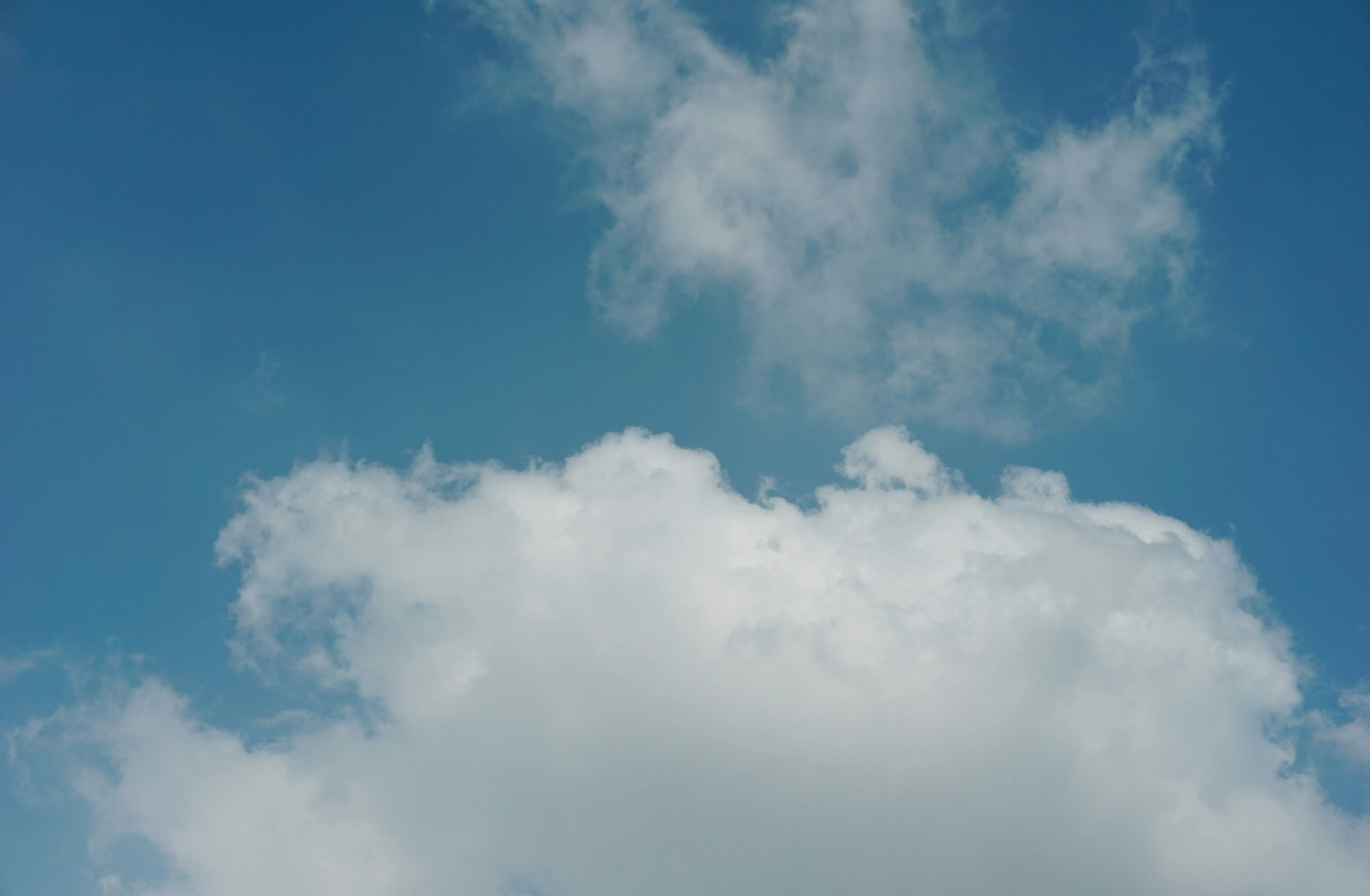 Bright Fluffy Clouds Drifting in a Clear Blue Sky Wallpaper