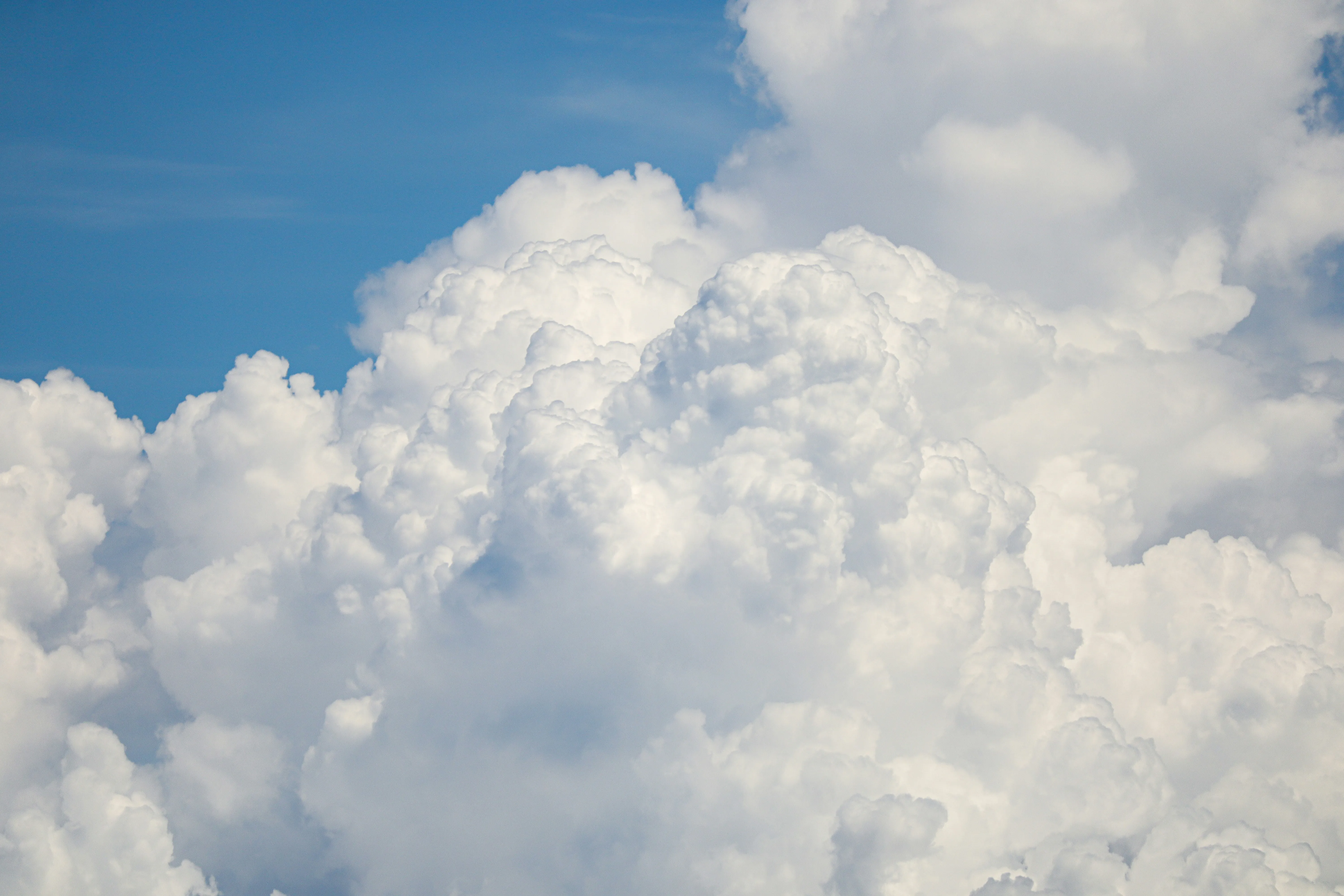 Bright White Fluffy Clouds in a Clear Blue Sky Wallpaper