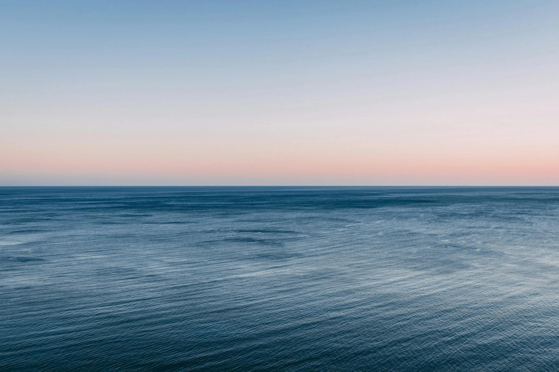 Calm Ocean Meets Sky in a Serene Blue Twilight Wallpaper