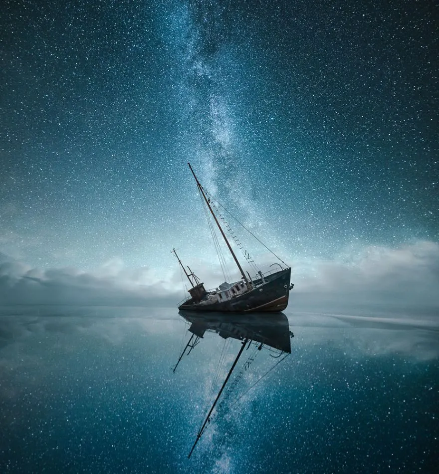 Calm Sailing Boat Floating on Still Water Under Stars Image