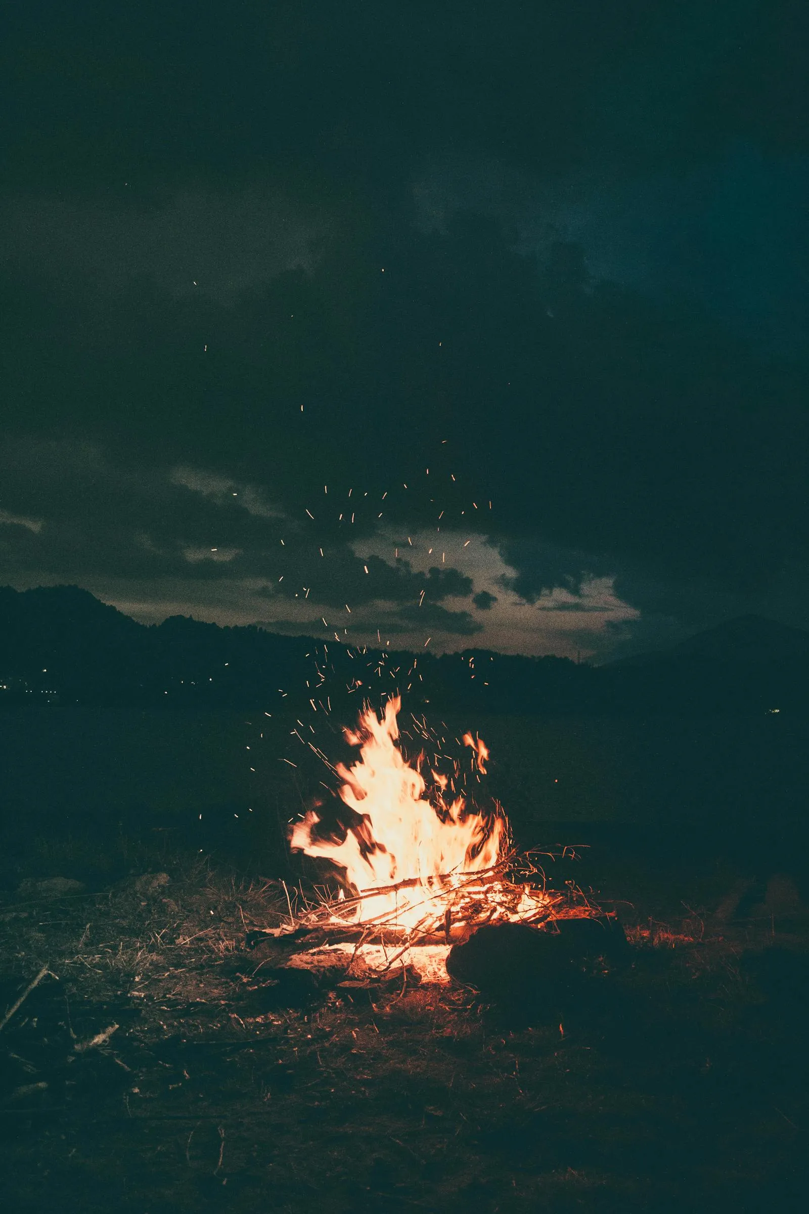 Campfire Burning Brightly in the Darkness with Clouds Above