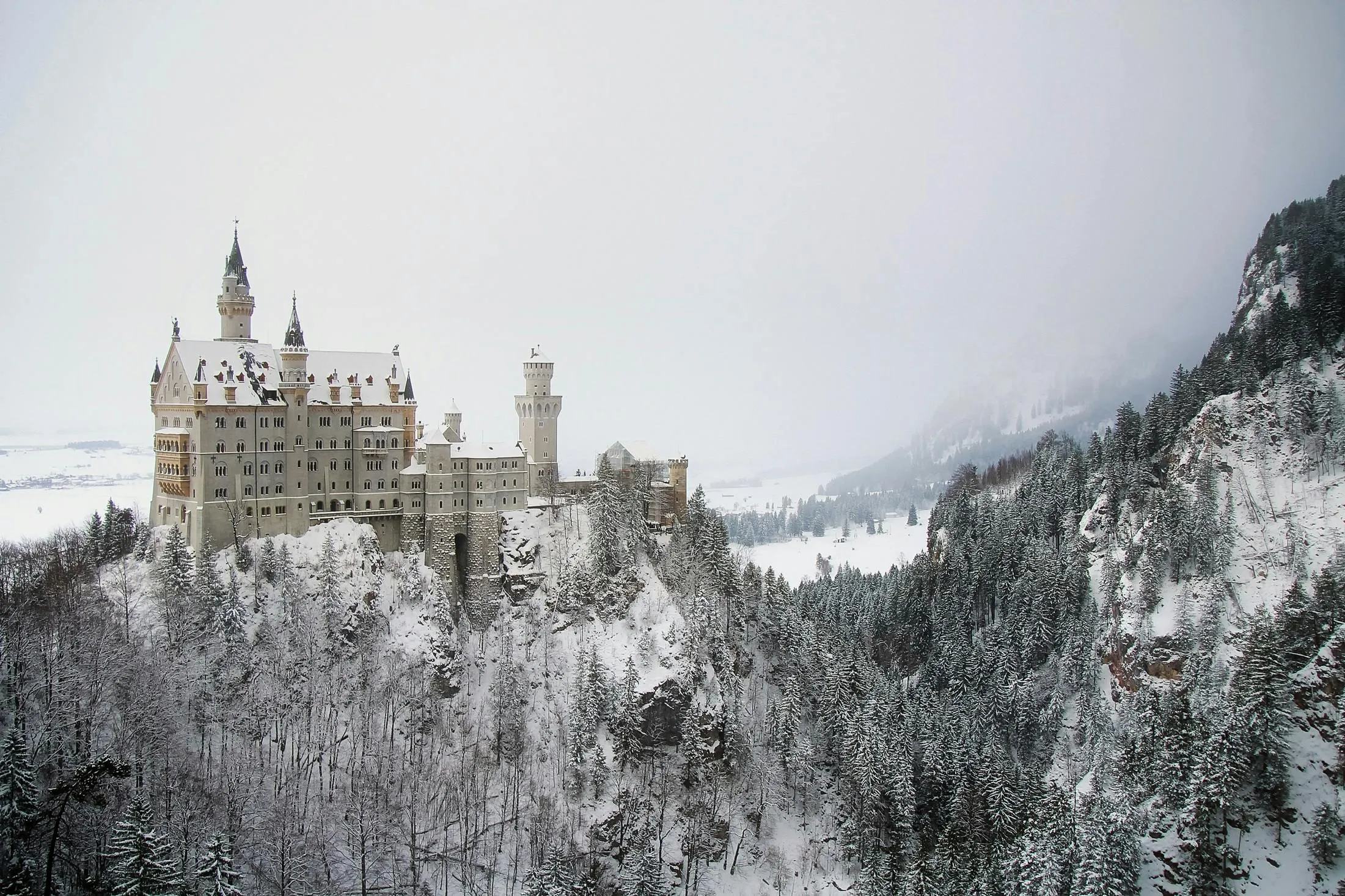 Castle Nestled in Snowy Forest Mountains in Winter Wallpaper