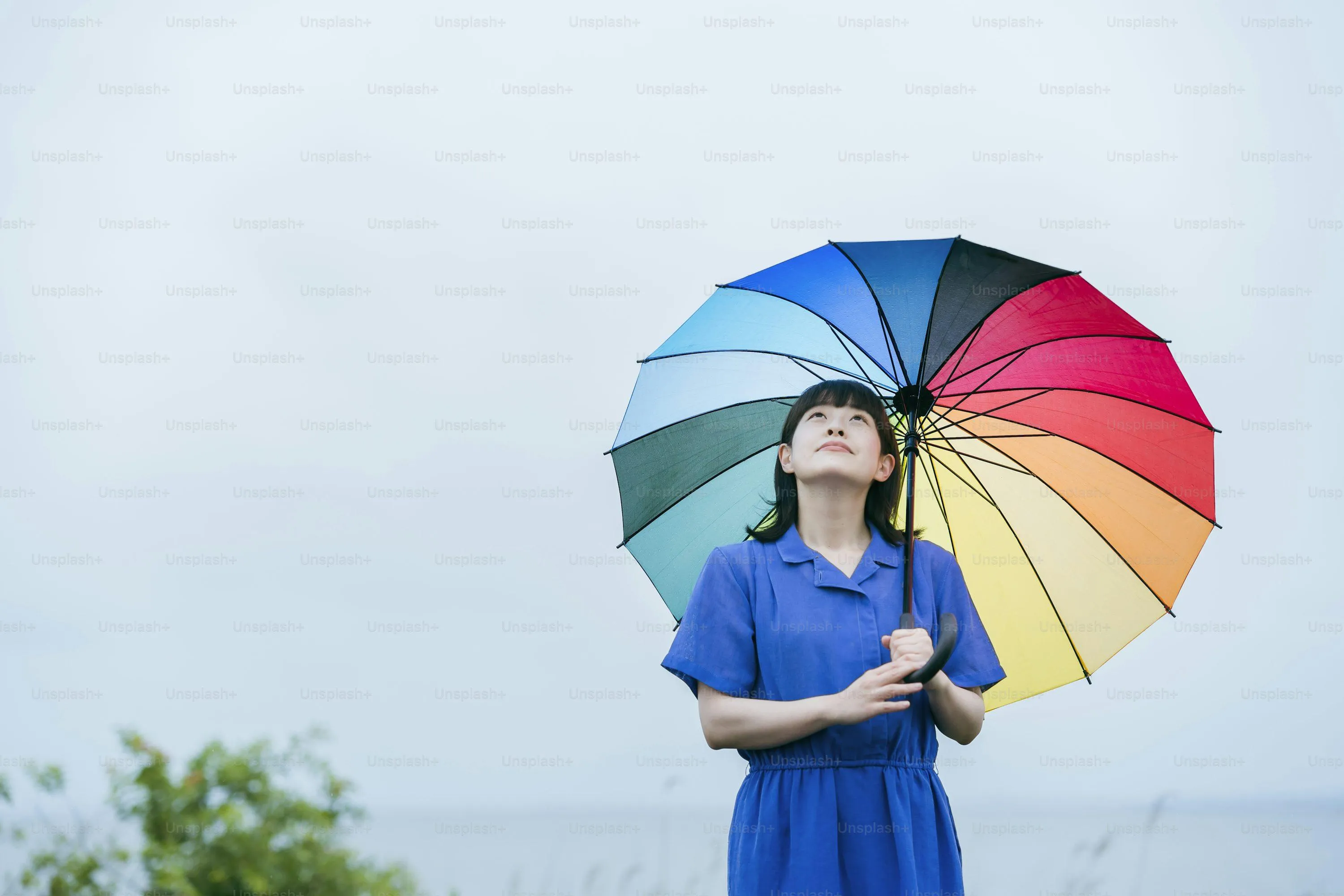 Child Holding Colorful Umbrella Standing in Rain