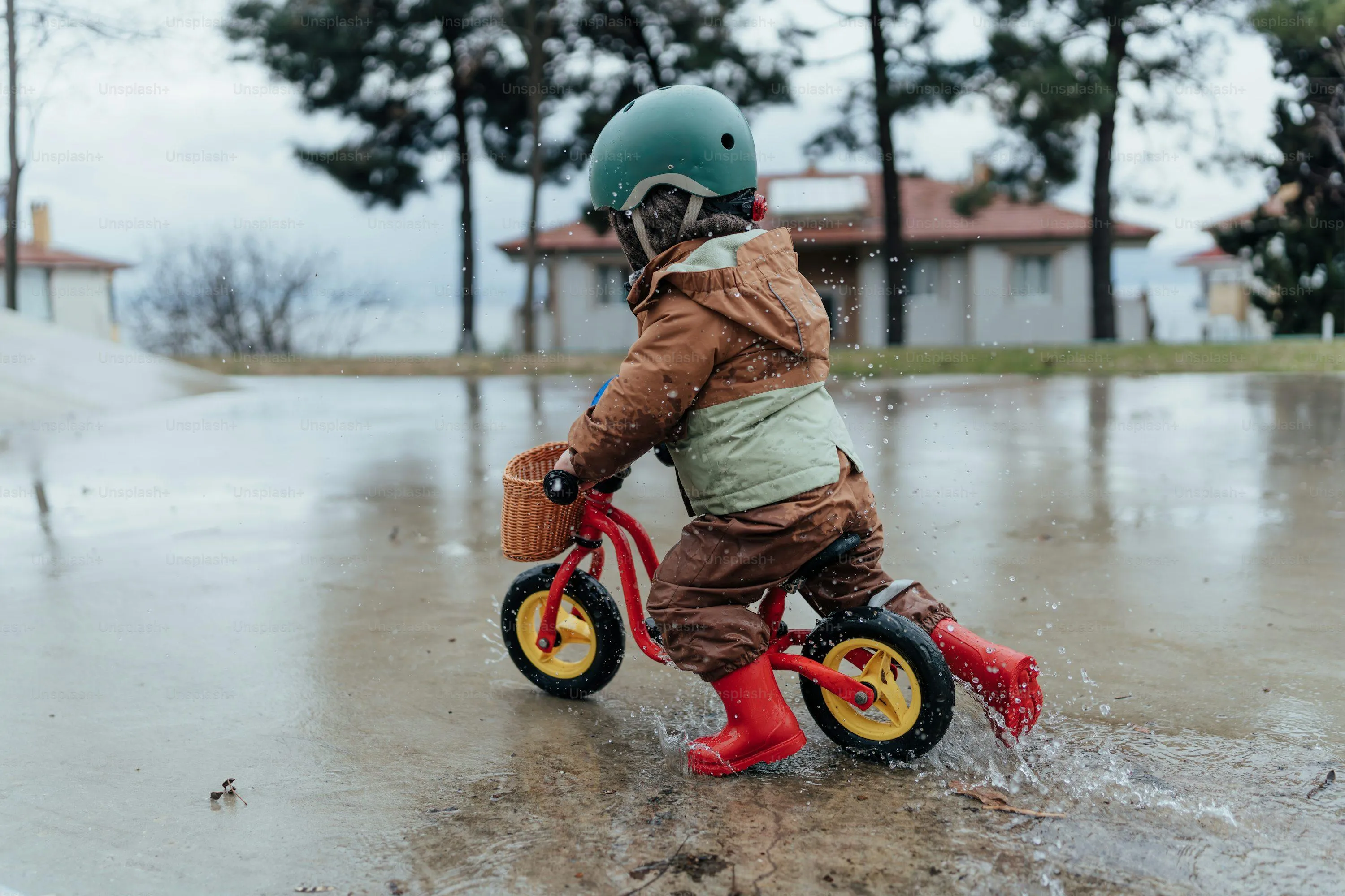 Child on Tricycle Splashing Through Puddles in Rainy Park