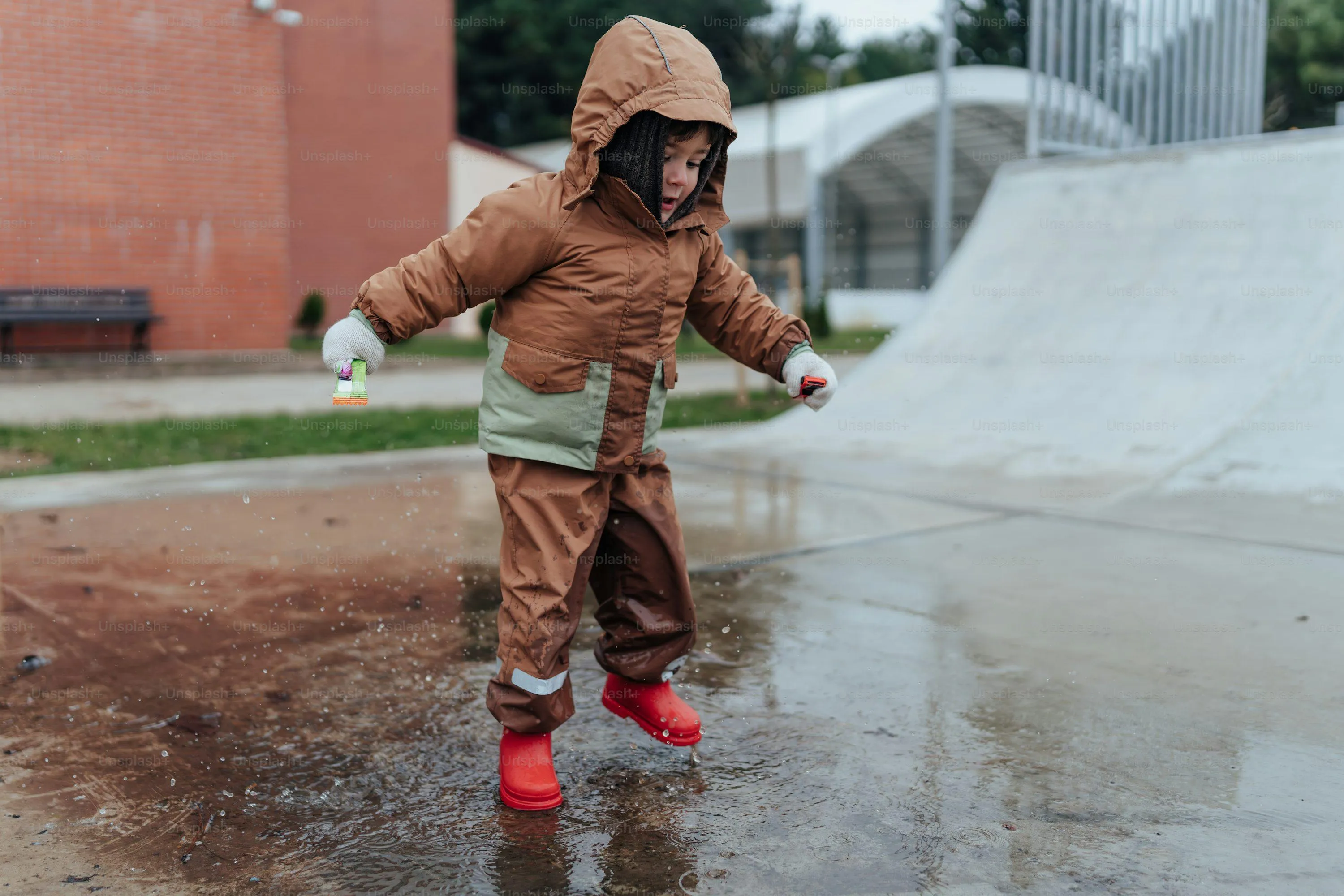 Child Playing with Water in Rain Wearing Protective Gear