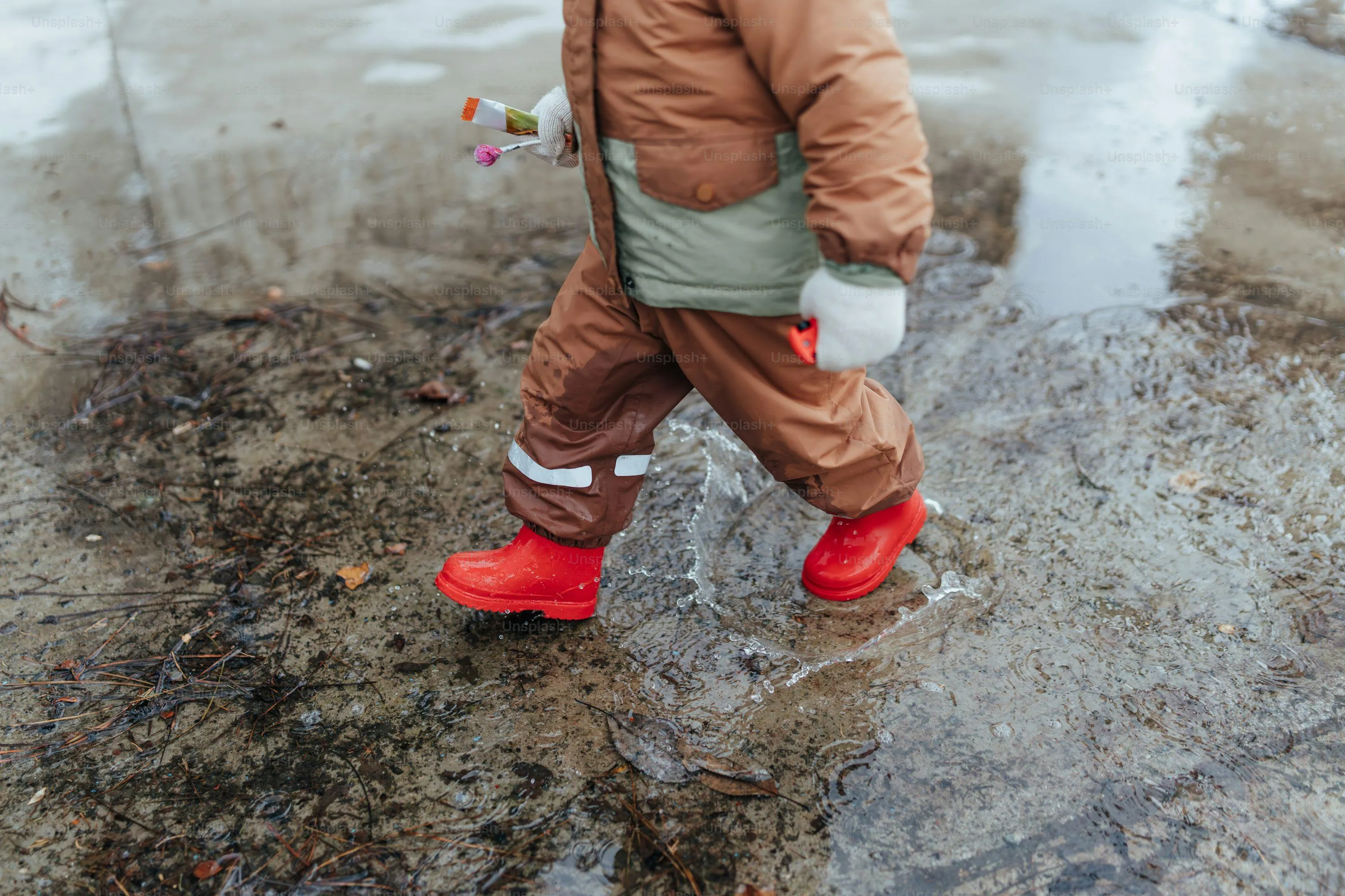 Child Splashing in Puddles with Bright Red Rain Boots