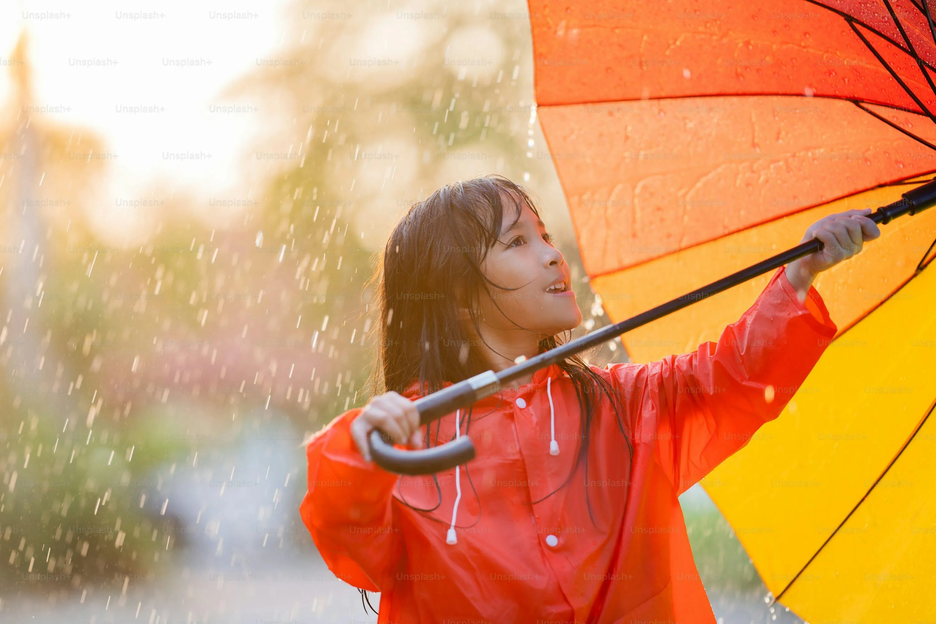 Child Wearing Orange Jacket Holding Umbrella in Rain