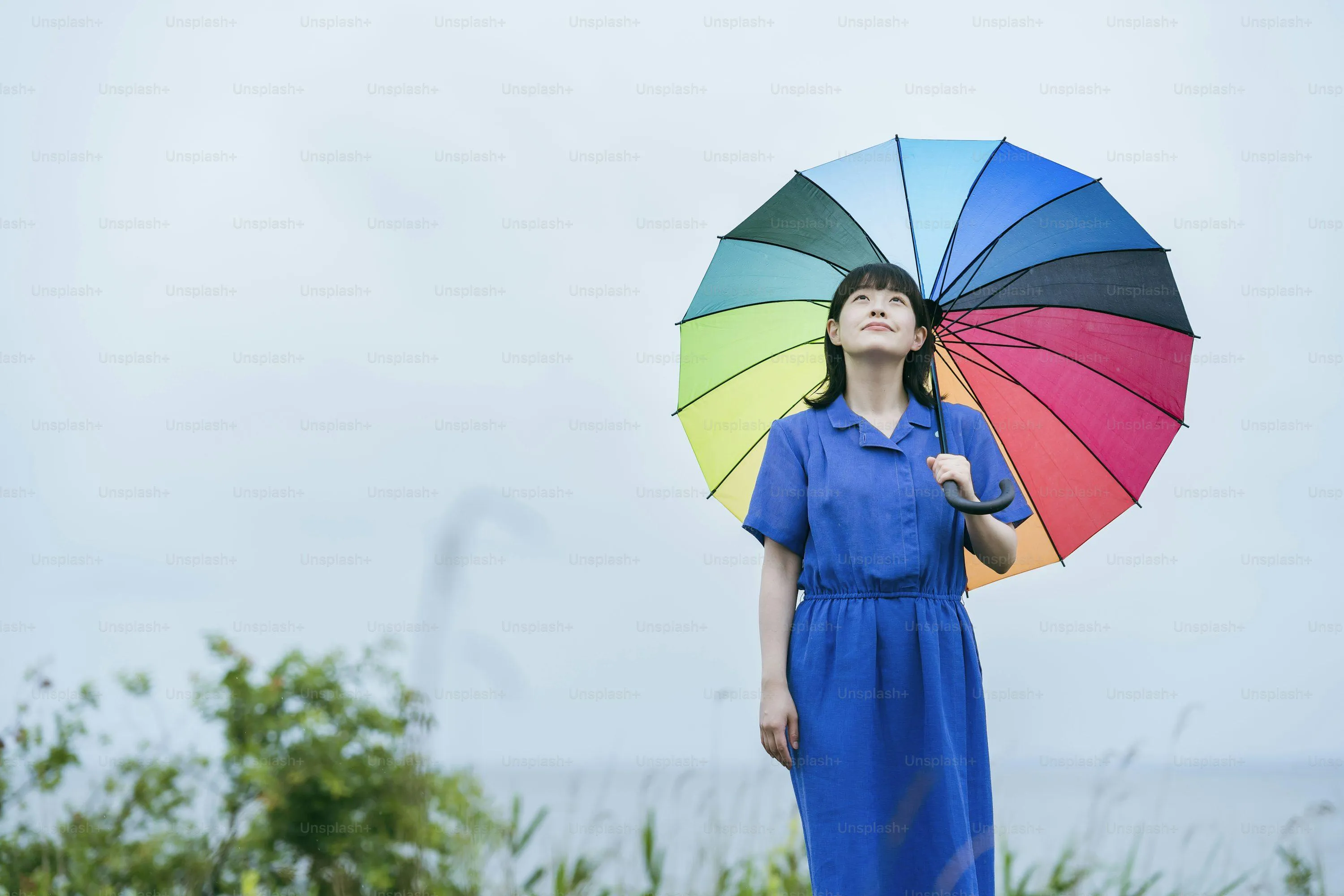 Child with Colorful Umbrella Standing in Rainy Field