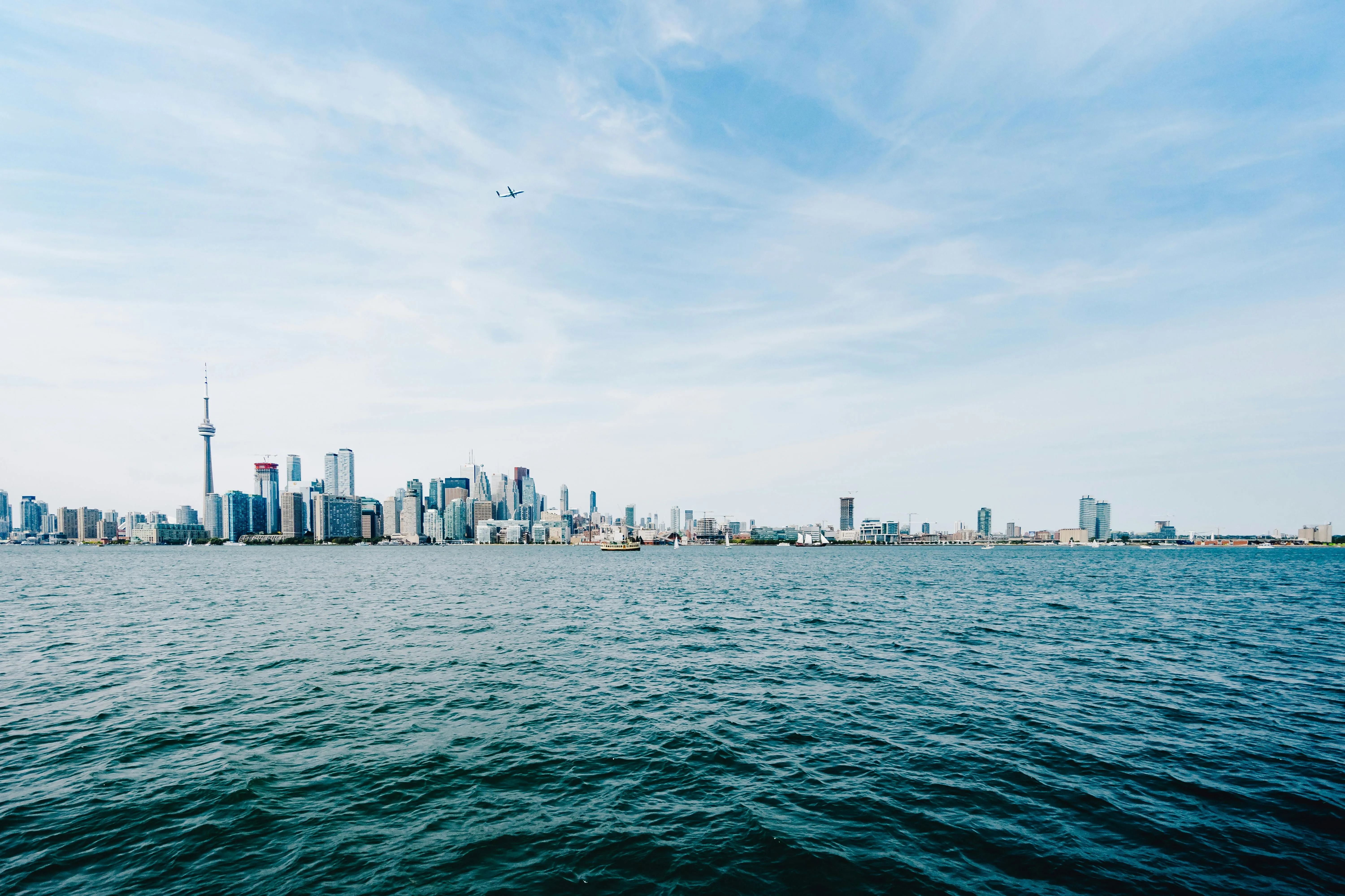 City Skyline From Water View Under Bright Blue Cloudy Sky