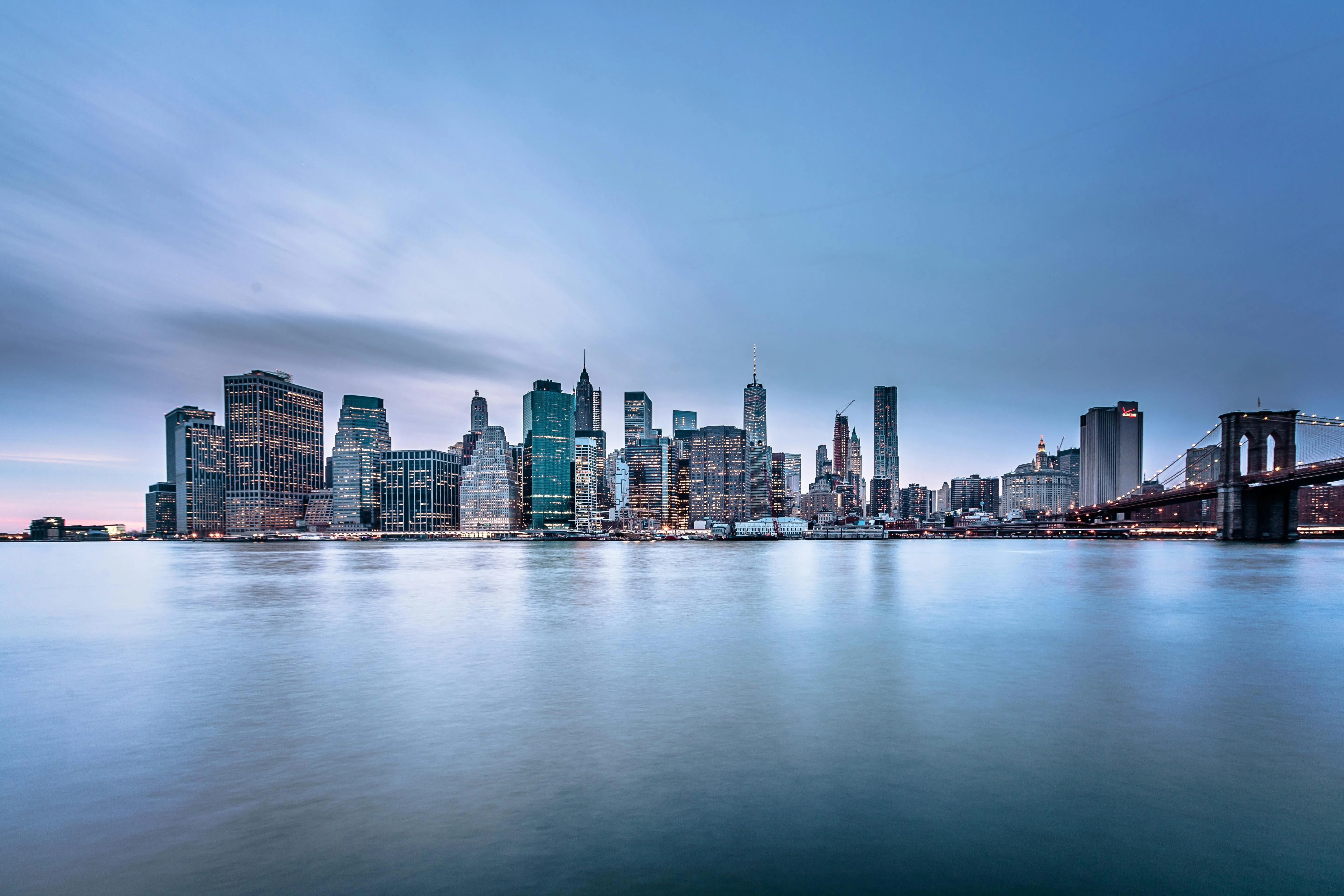 City Skyline Reflected in Calm Water During Daytime