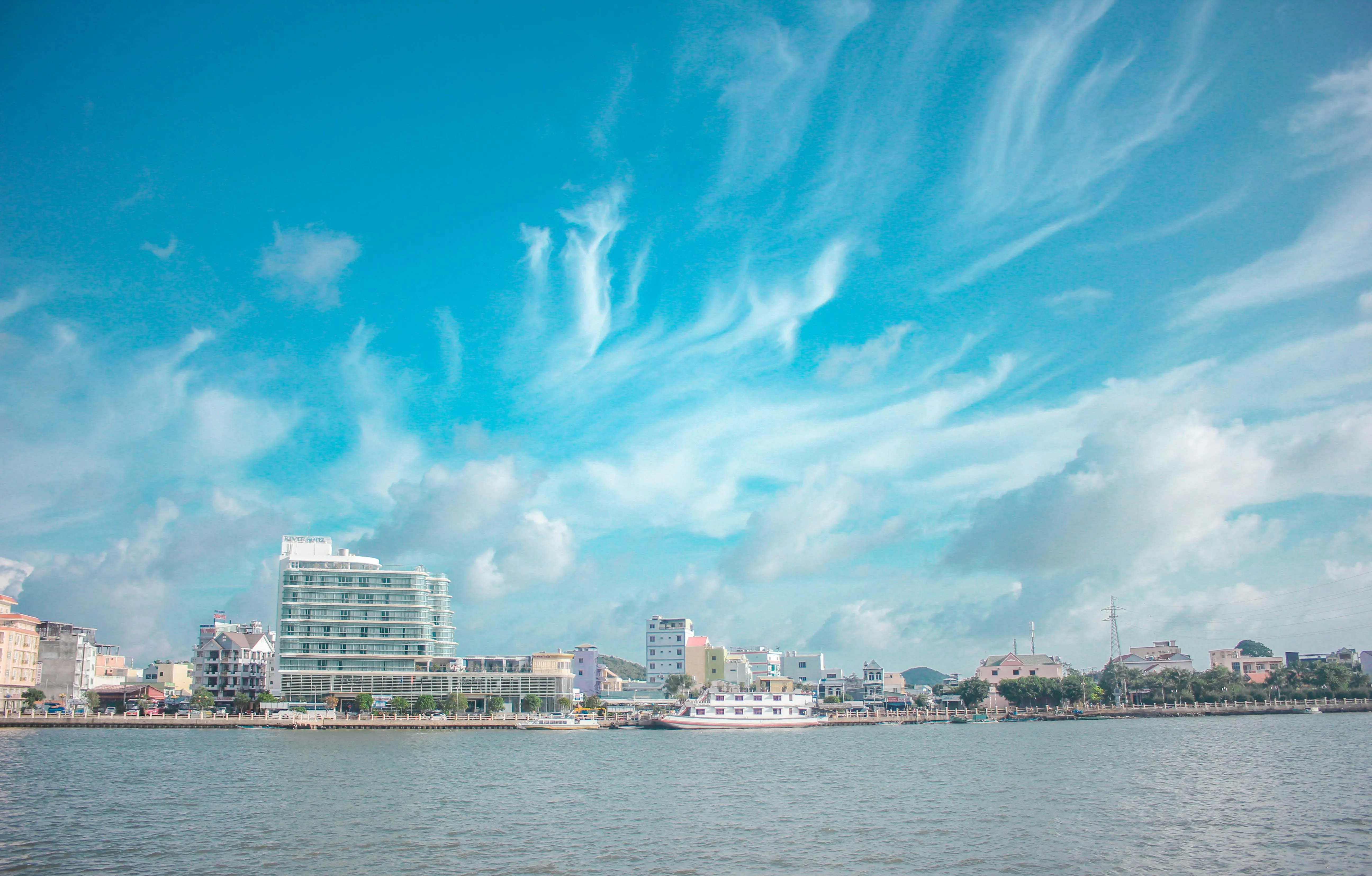 City Skyline Under a Bright Blue Sky with Wispy Clouds