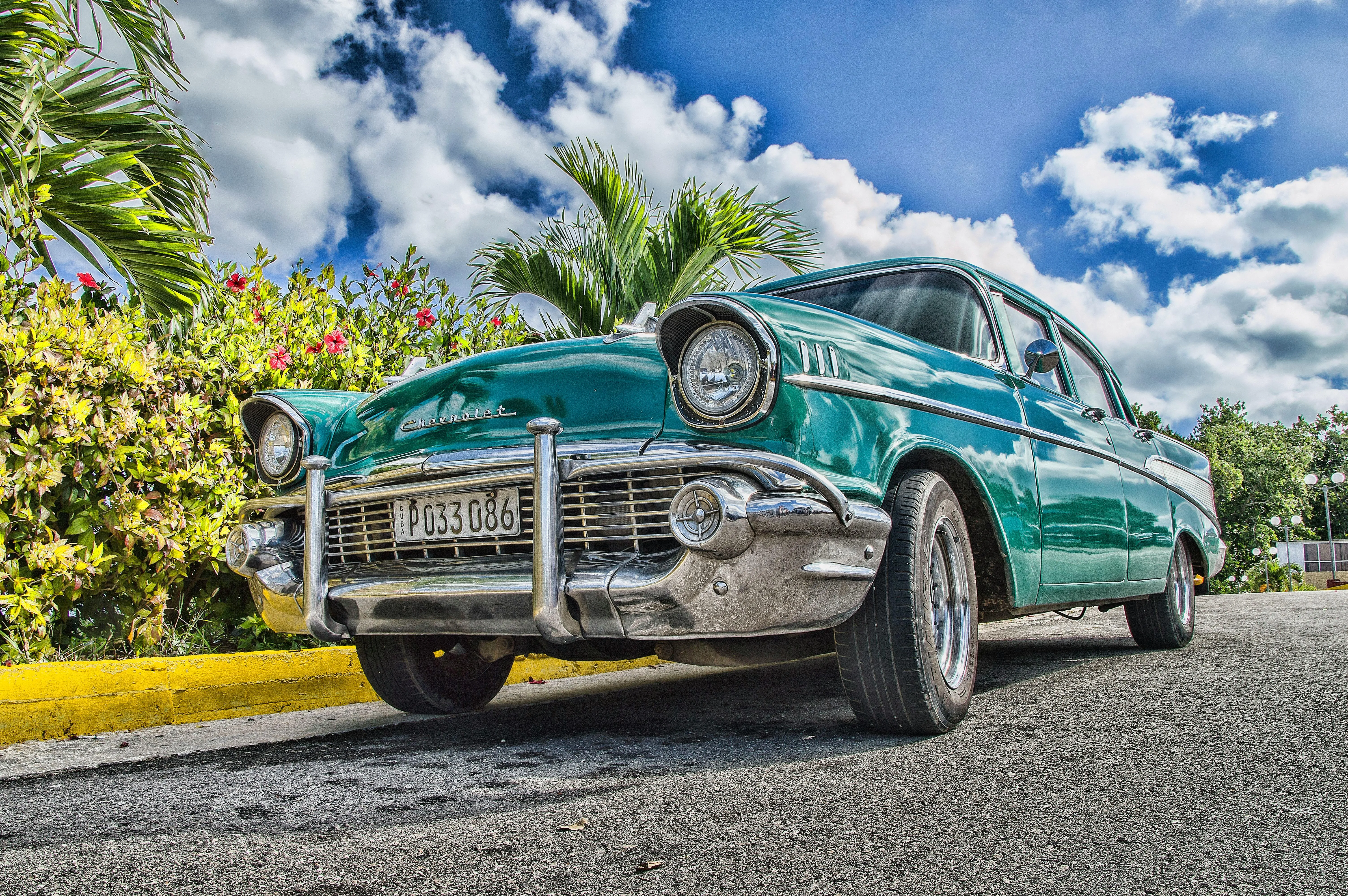 Classic Car on Roadside Under a Bright Blue Cloudy Sky