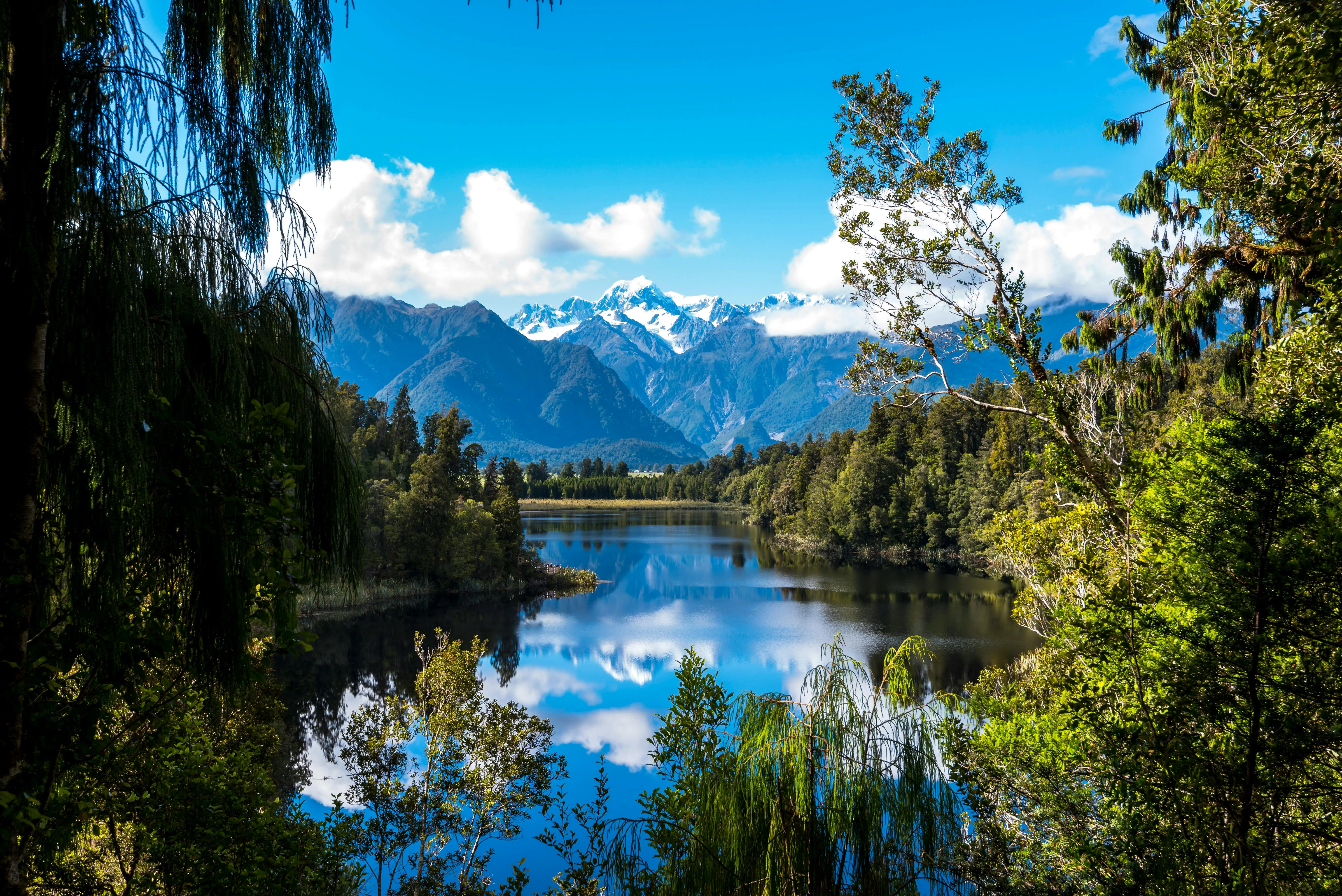 Clear Blue Lake Reflecting Forest and Mountains in Sunshine